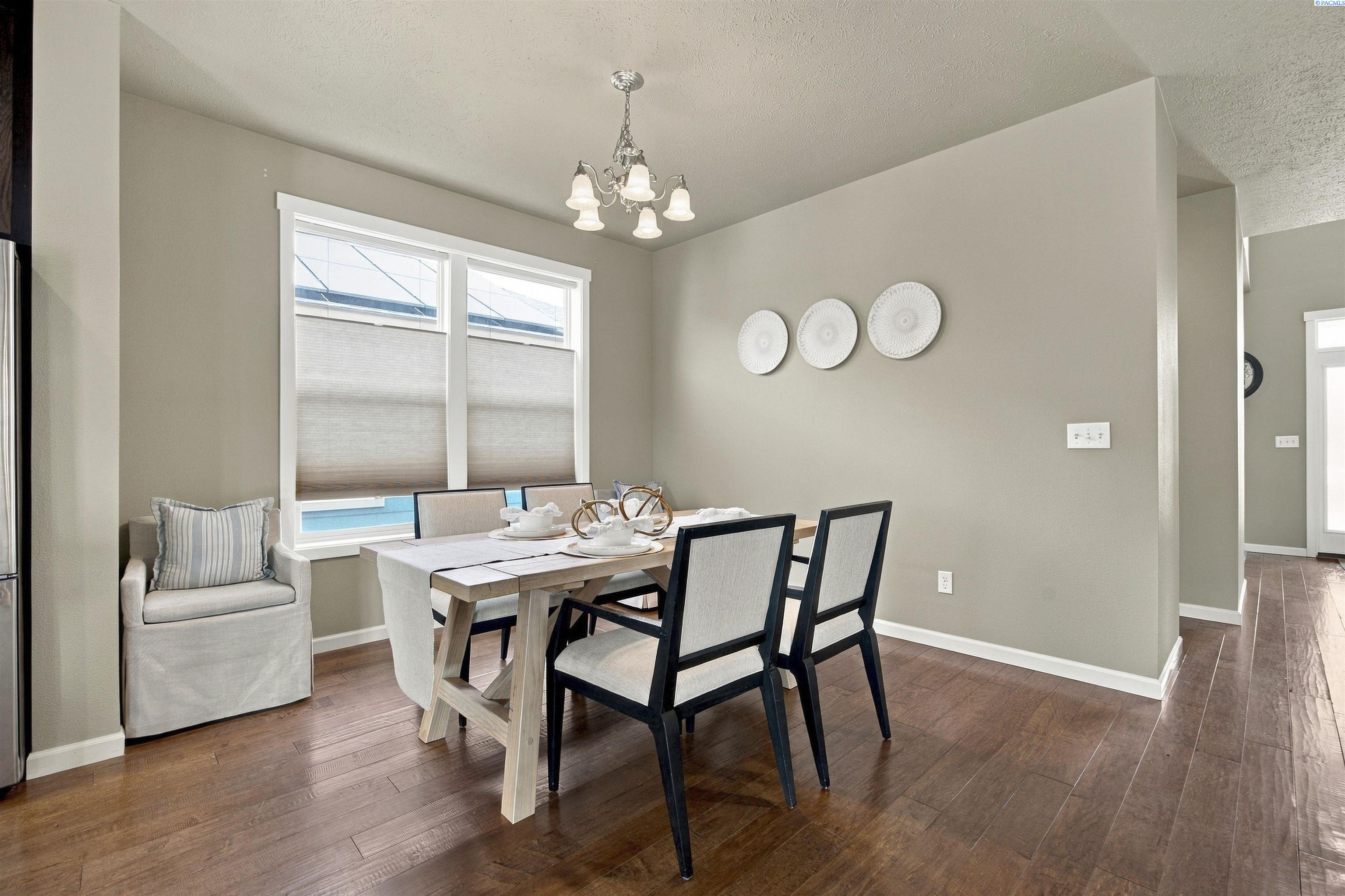 Staged dining room with a set table, chandelier, and large shaded windows.