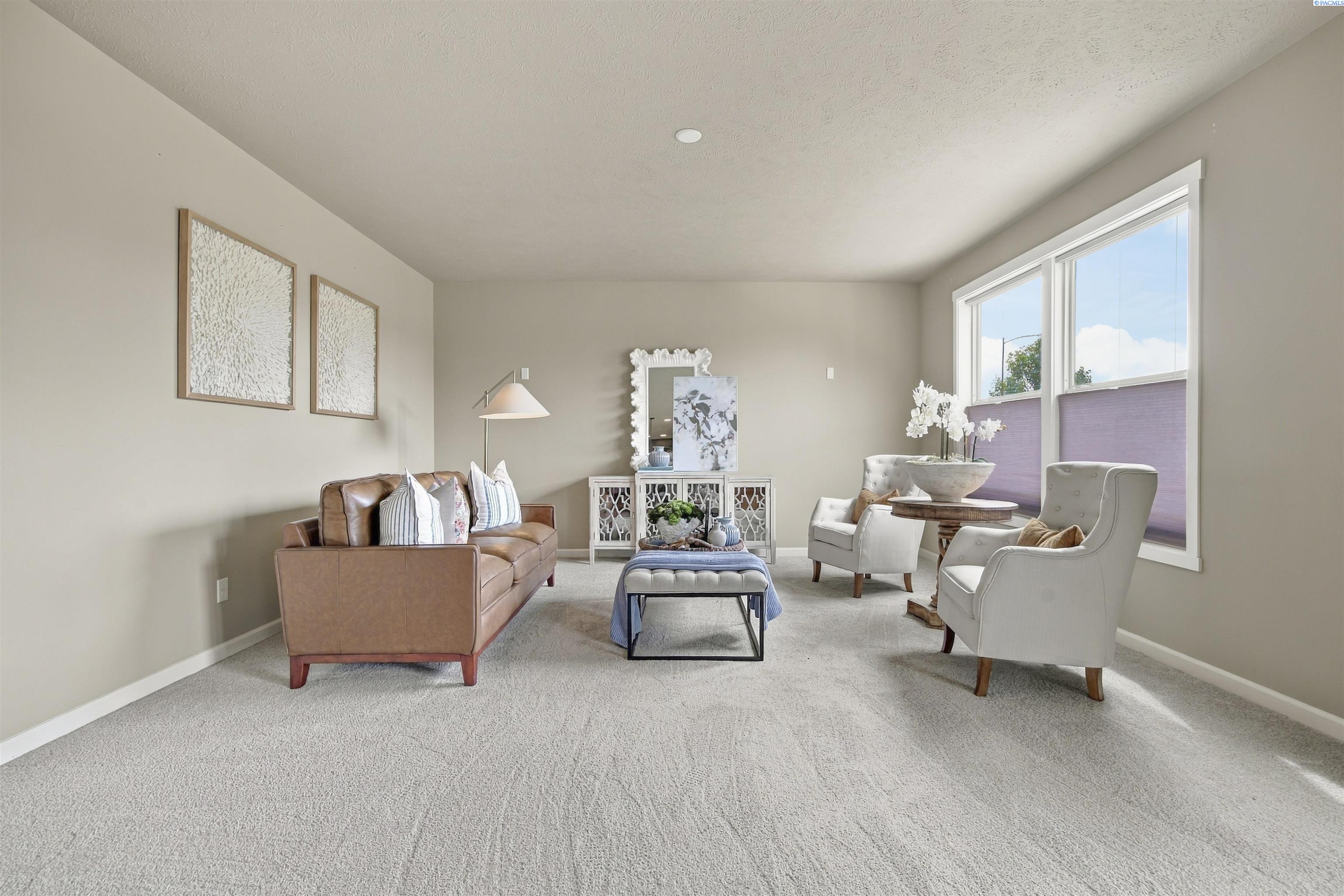Staged living room with a brown leather sofa, white armchairs, and large windows with purple shades.