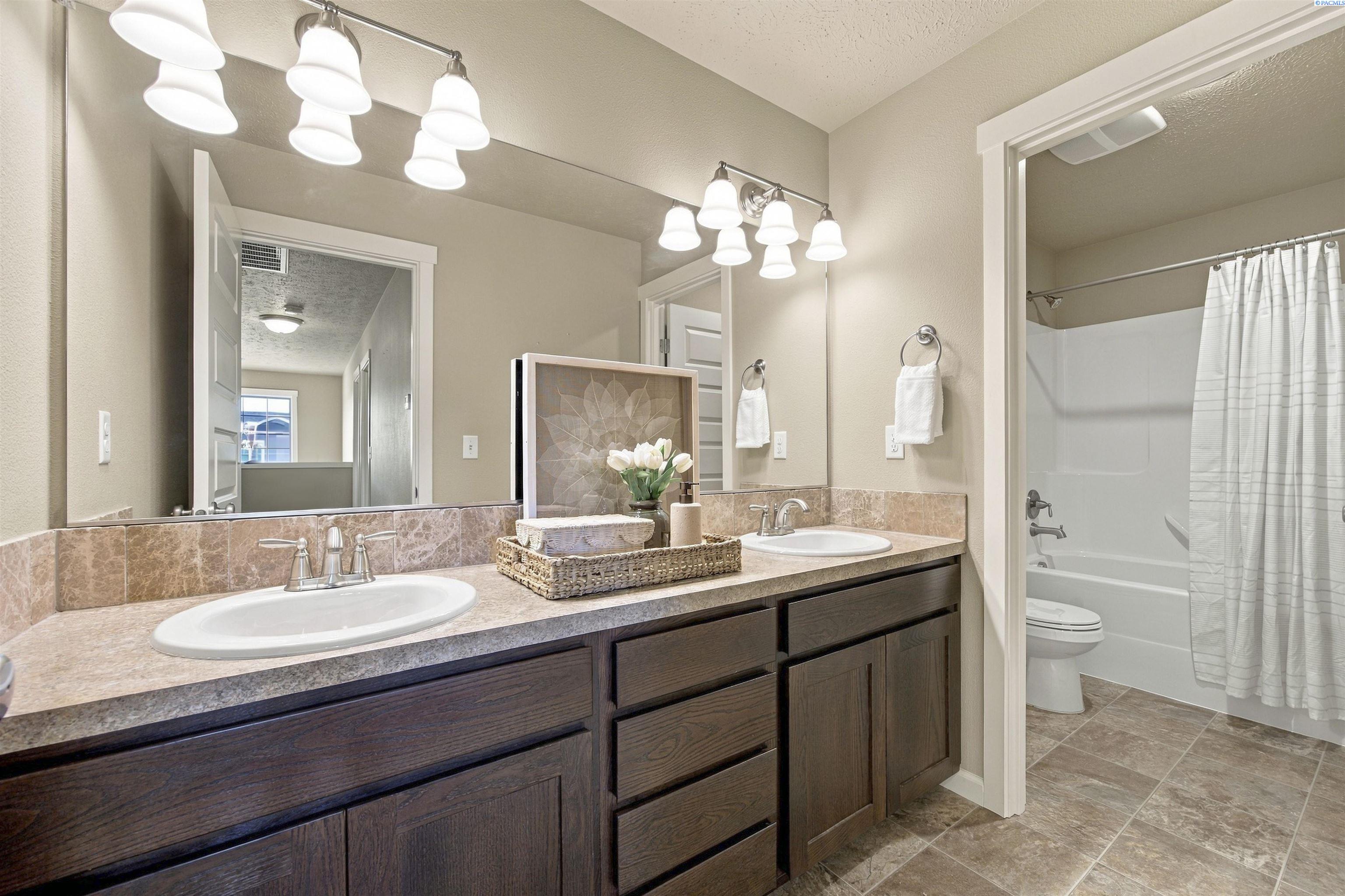 Bathroom with a dark wood double vanity and a tub-shower behind a white curtain.