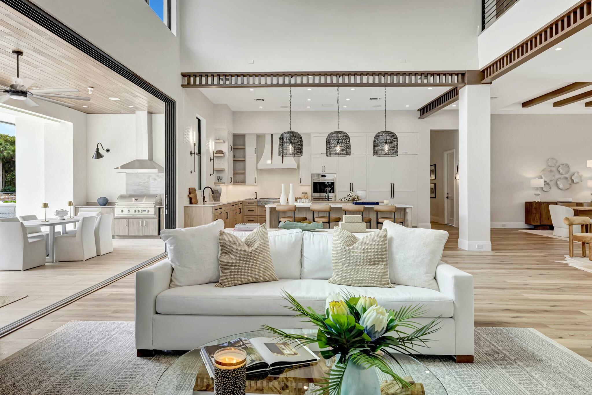 Open-plan living room with a white sofa, kitchen island, and sliding doors to a covered patio.