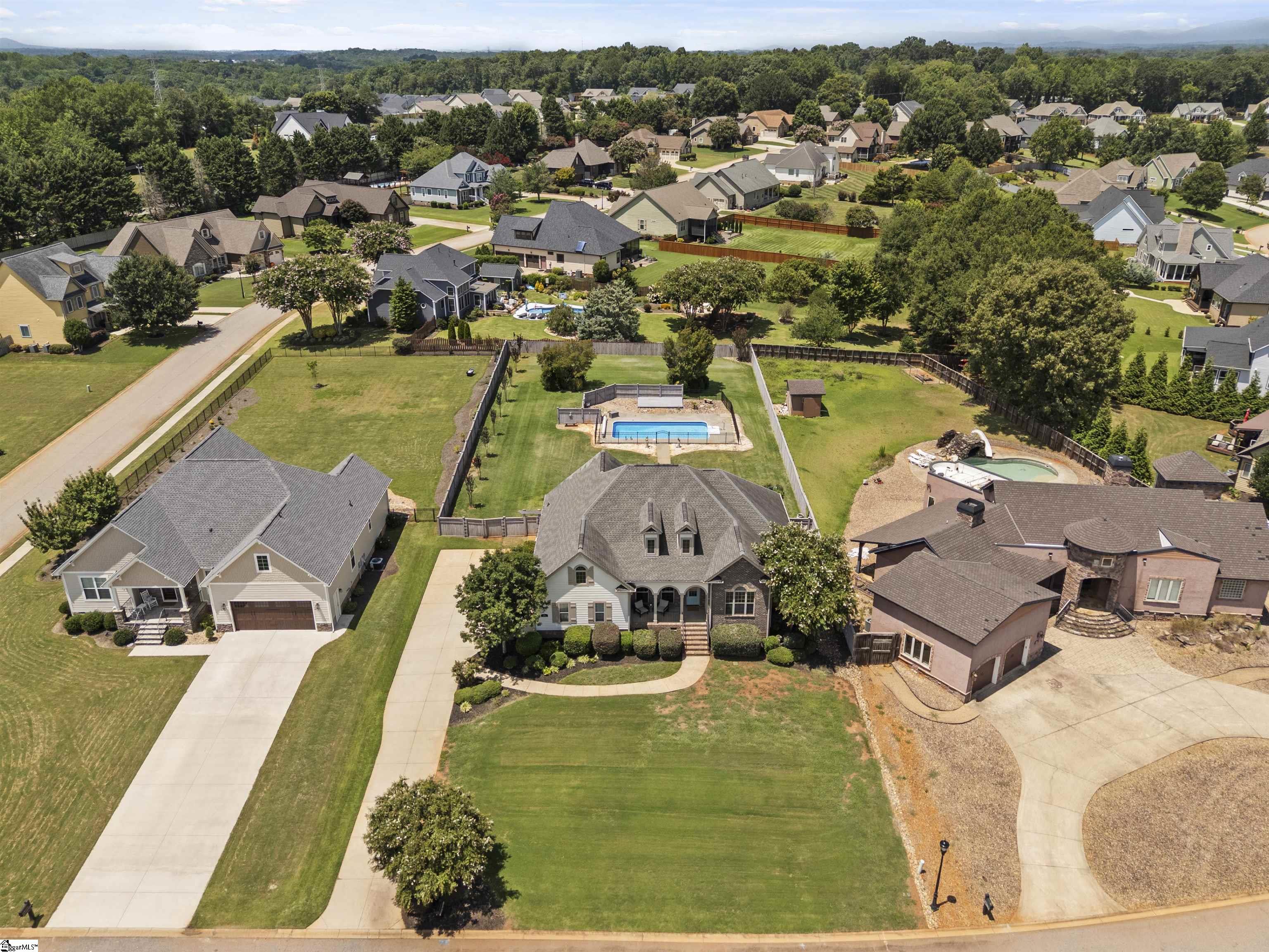 Aerial view of 127 Carshalton Drive, showing its front lawn, fenced backyard, and swimming pool.
