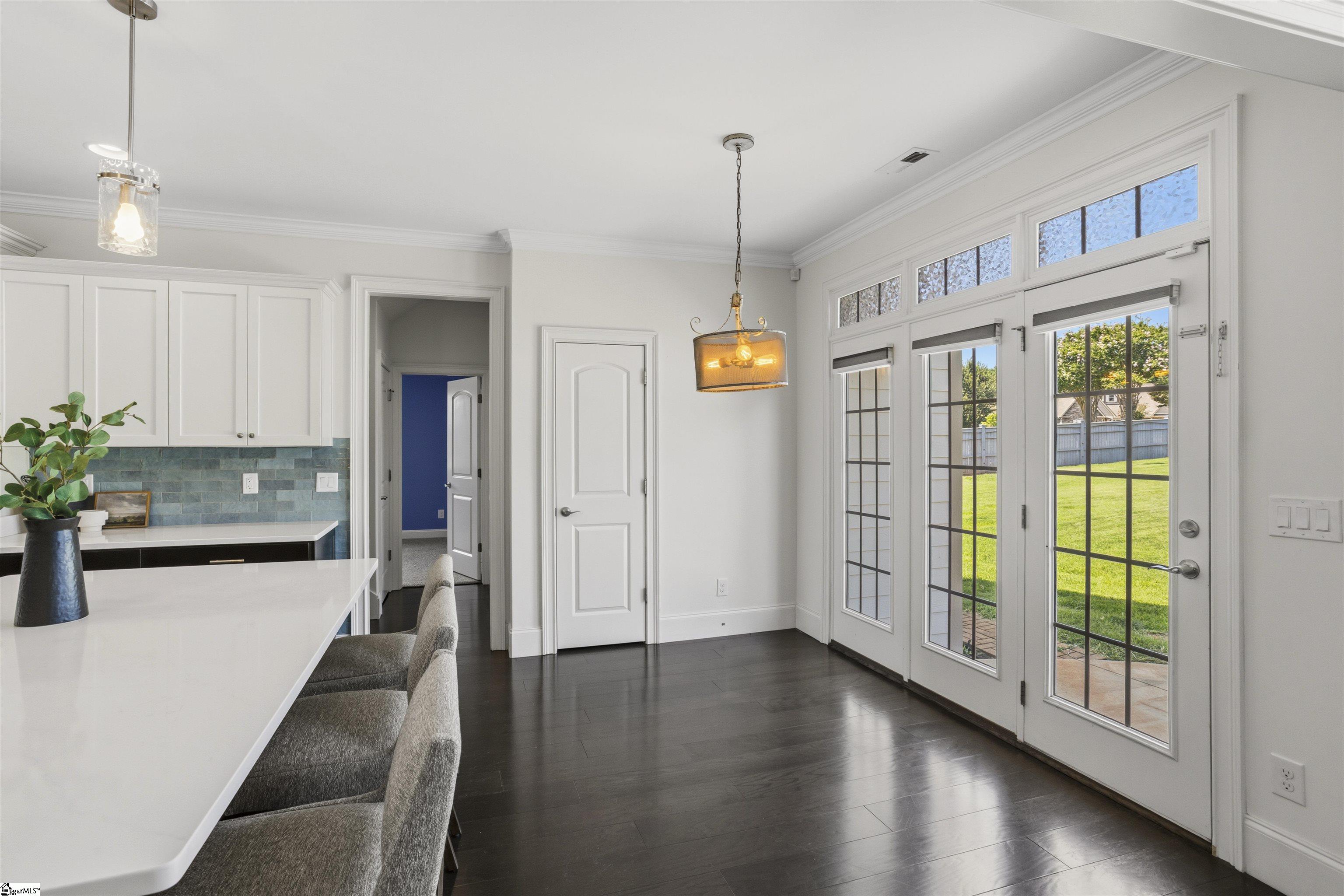 Kitchen with a white island and tall glass doors overlooking a fenced backyard.