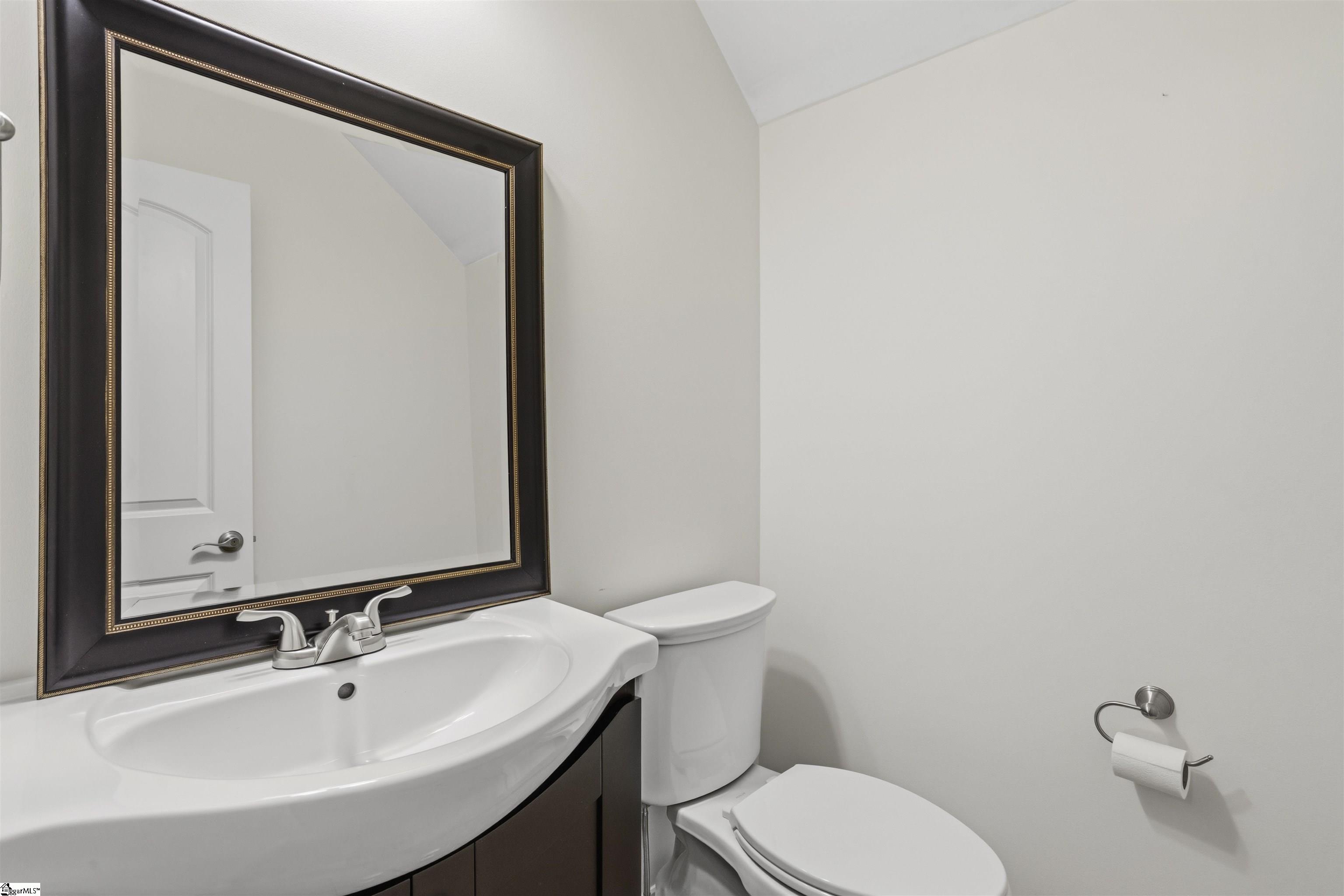 Small bathroom with a white vanity, large framed mirror, and toilet.