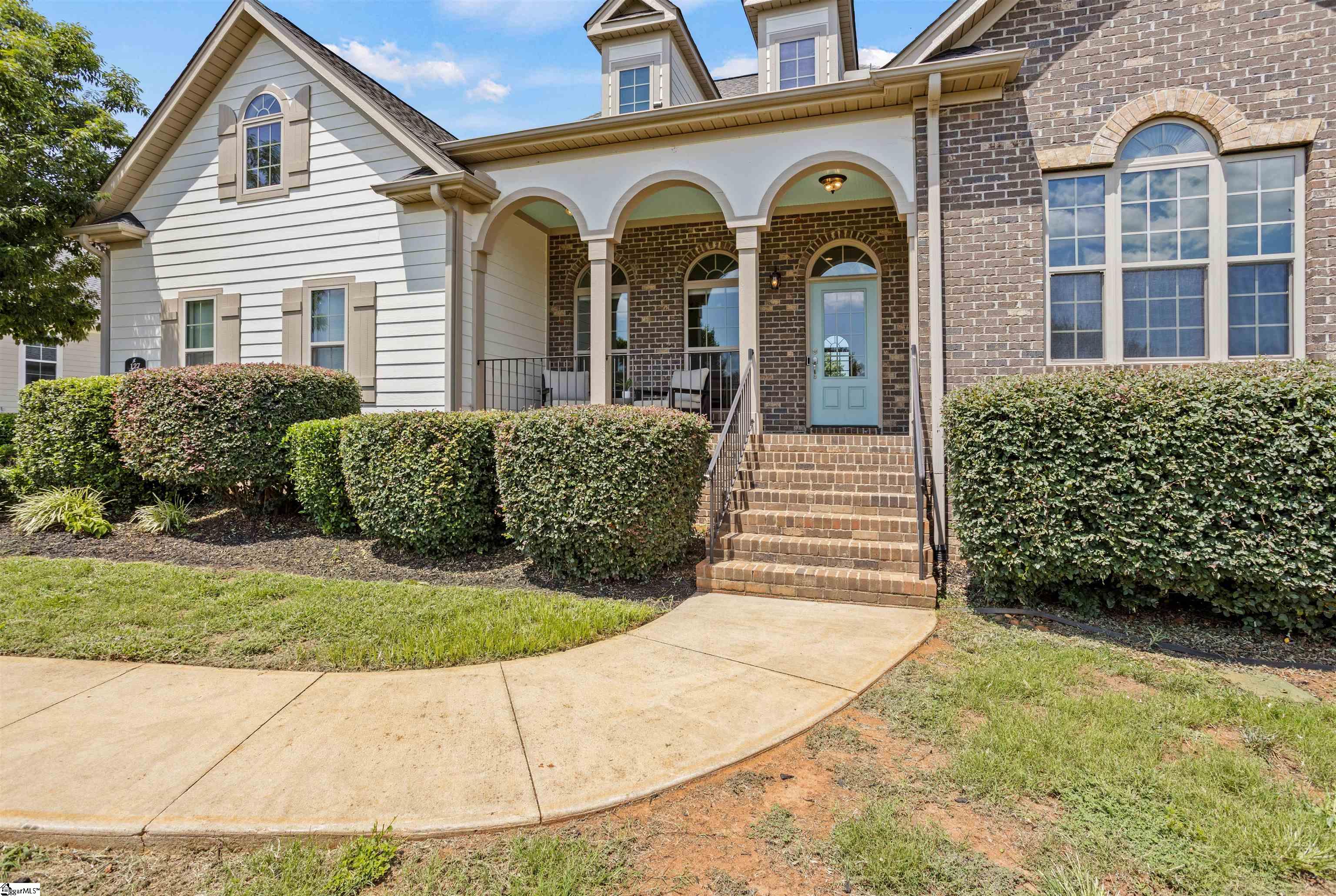 House front with an arched covered porch, pale blue door, brick steps, and curved walkway.