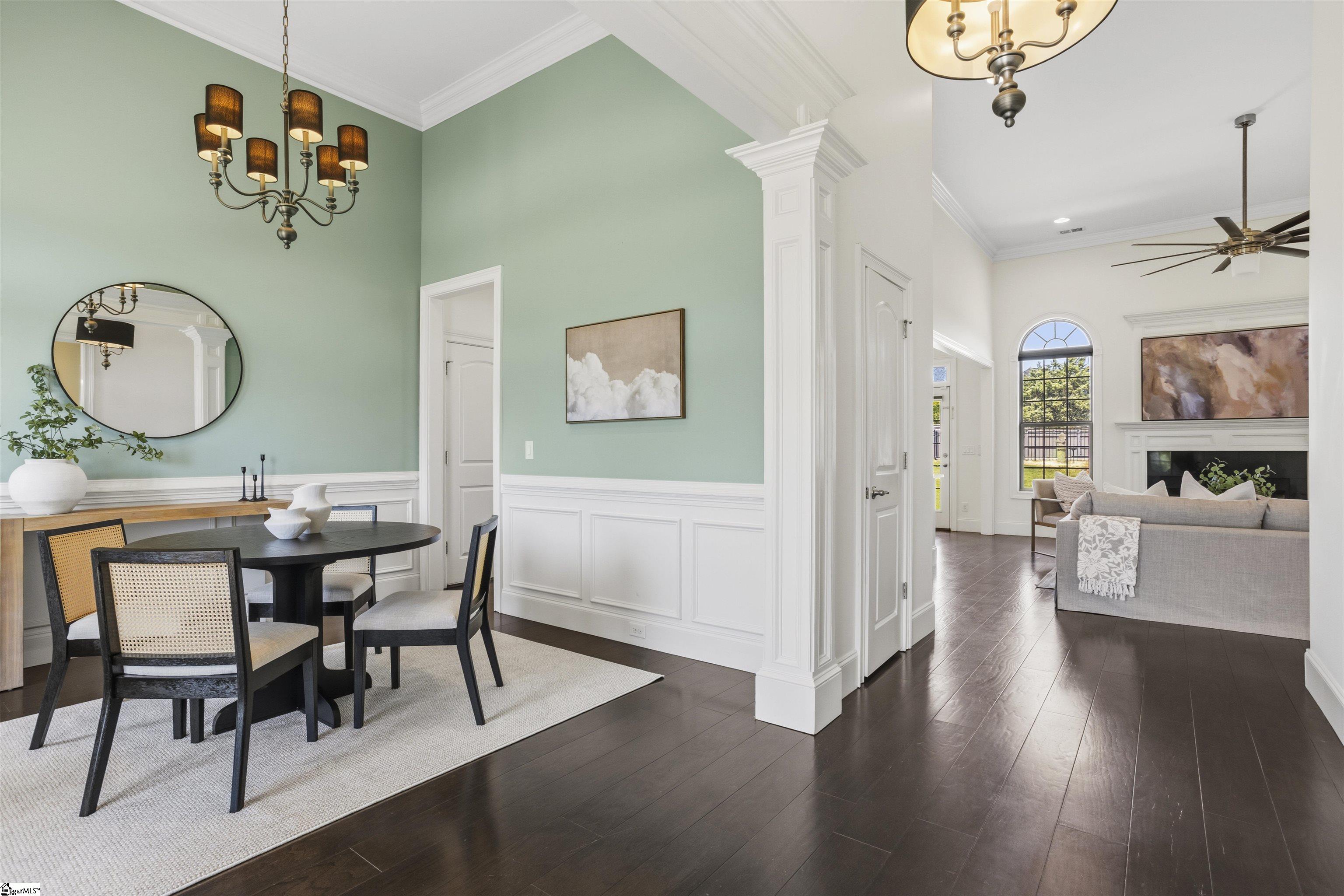 Dining room with mint-green walls and a chandelier opening into a living room with a fireplace.