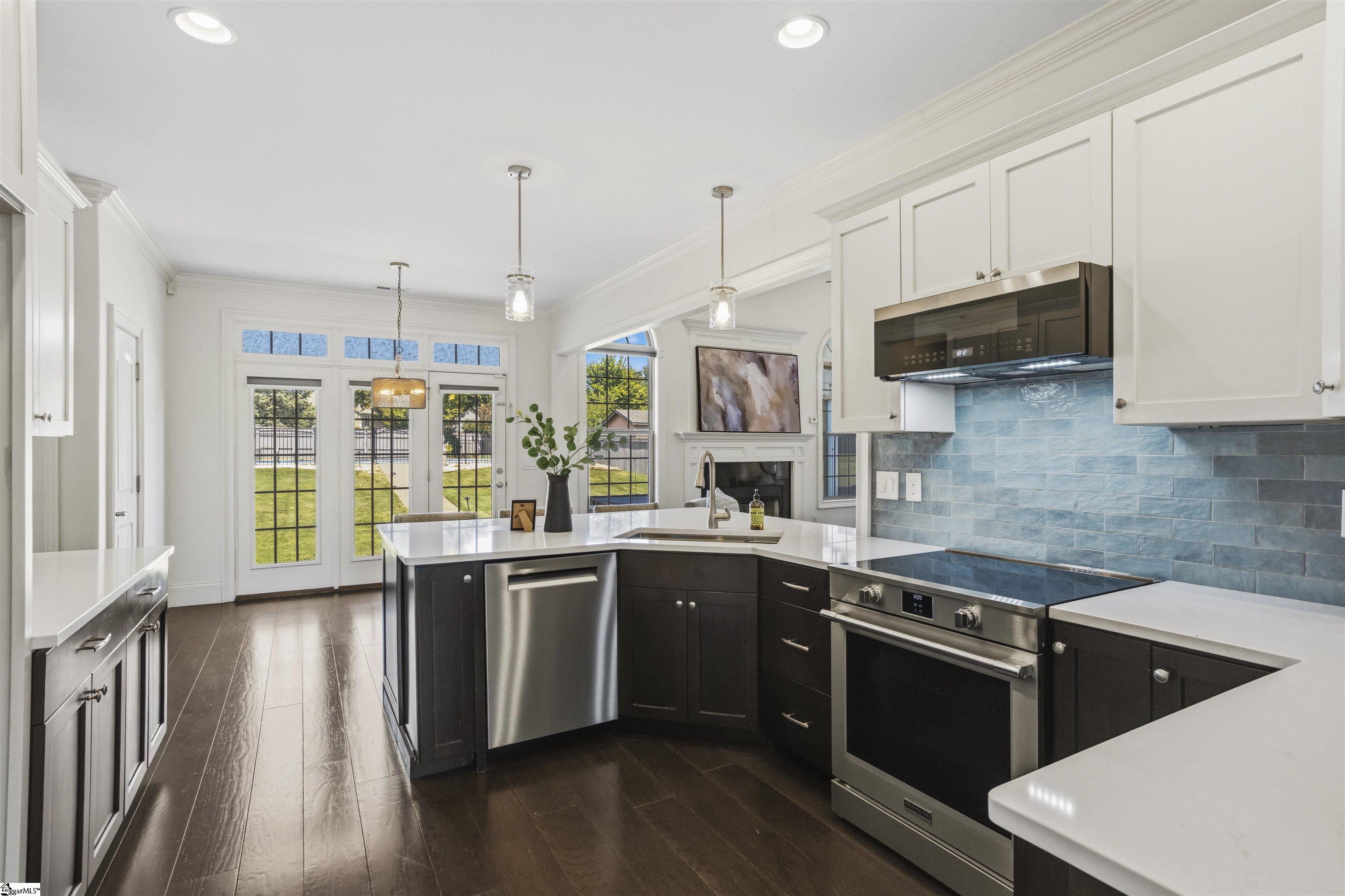 Kitchen with blue tile backsplash, stainless steel appliances, and French doors opening to a lawn.