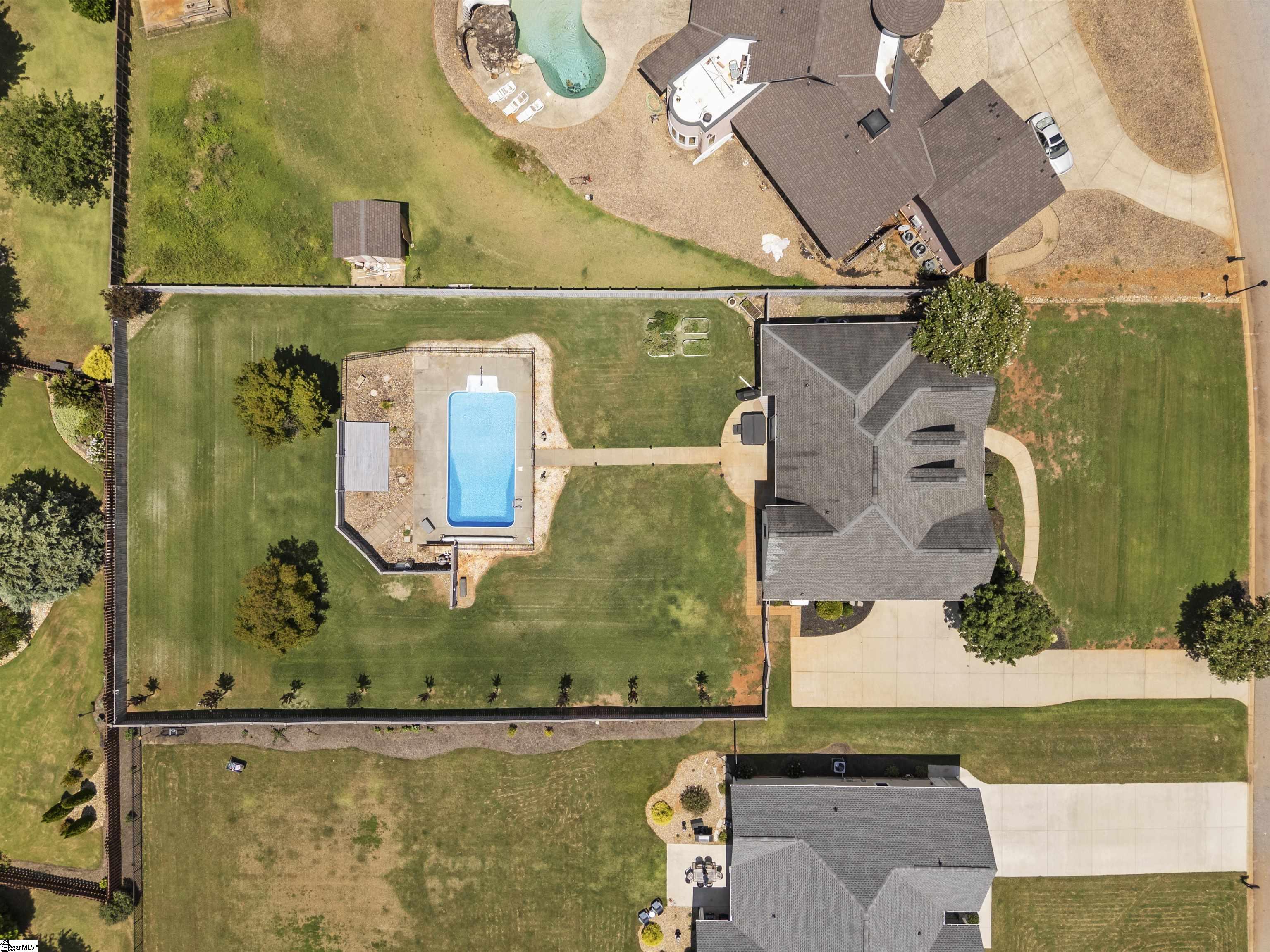 Aerial view of the home, fenced lawn, and rectangular backyard swimming pool.