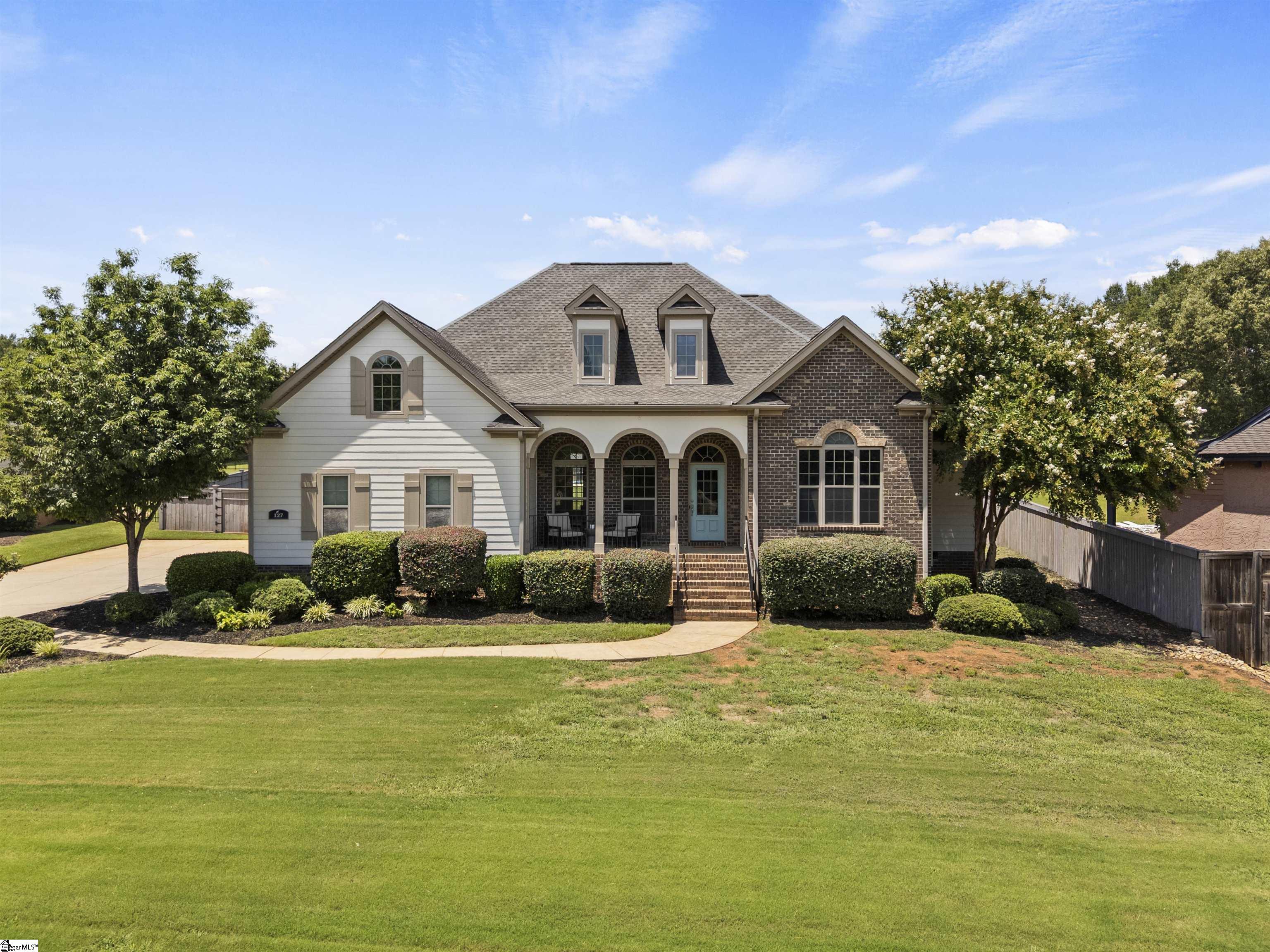 Two-story home with brick accents, an arched front porch, blue door, and broad lawn.