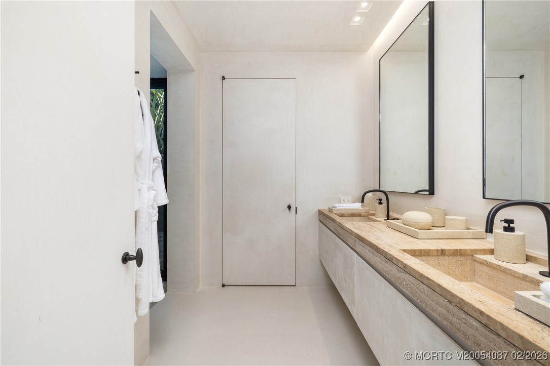 Modern bathroom with a long double stone vanity, two sinks, and black faucets.