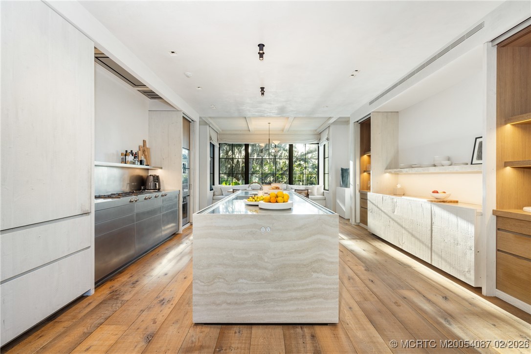 Modern kitchen with a large stone island, stainless appliances, and wide plank wood floors.