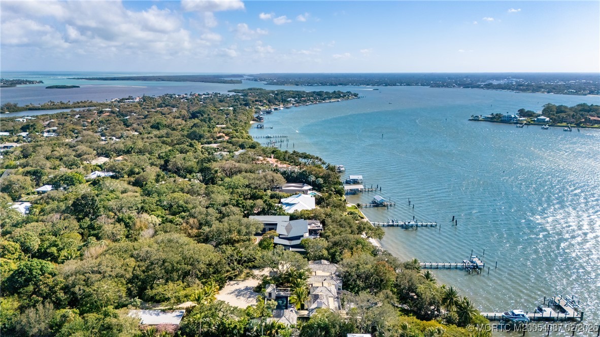Aerial waterfront homes and docks along a broad blue waterway.