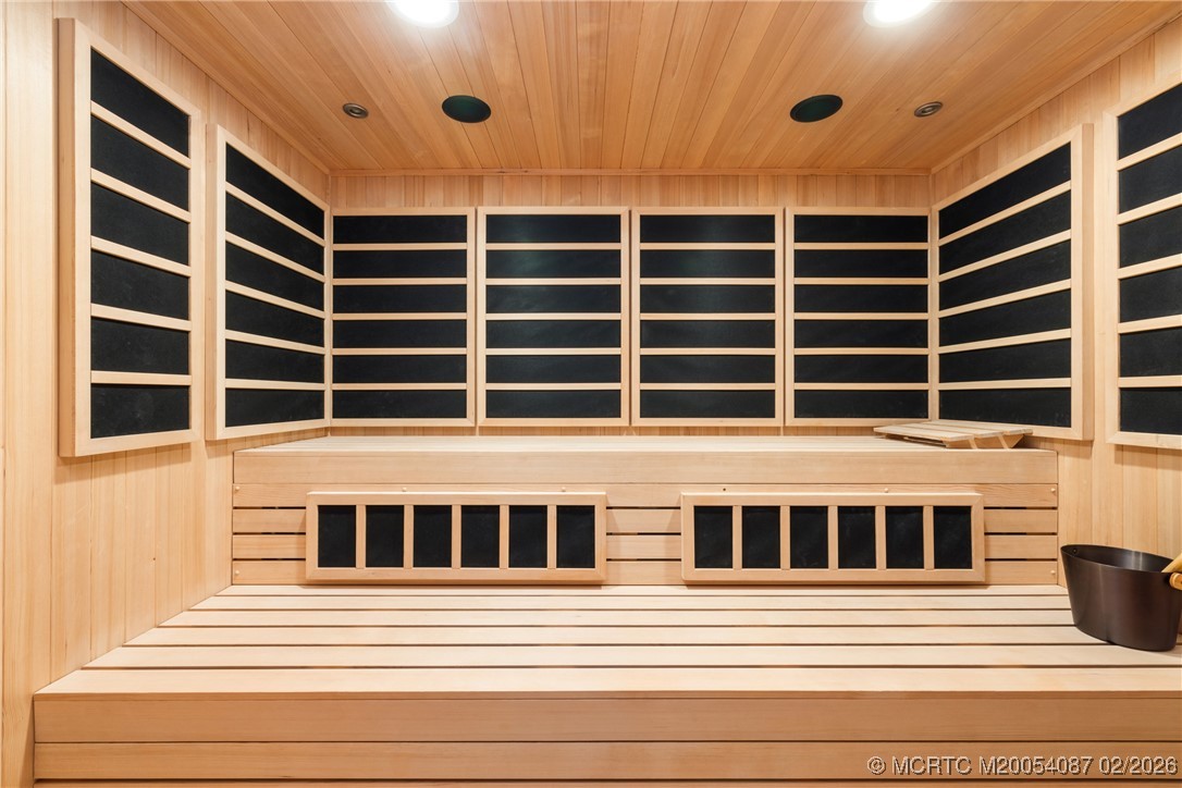 Wood-paneled sauna with tiered benches and dark inset wall panels.