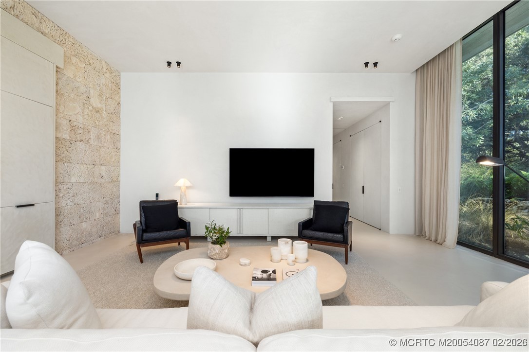 Living room with a stone accent wall, black lounge chairs, and floor-to-ceiling windows.