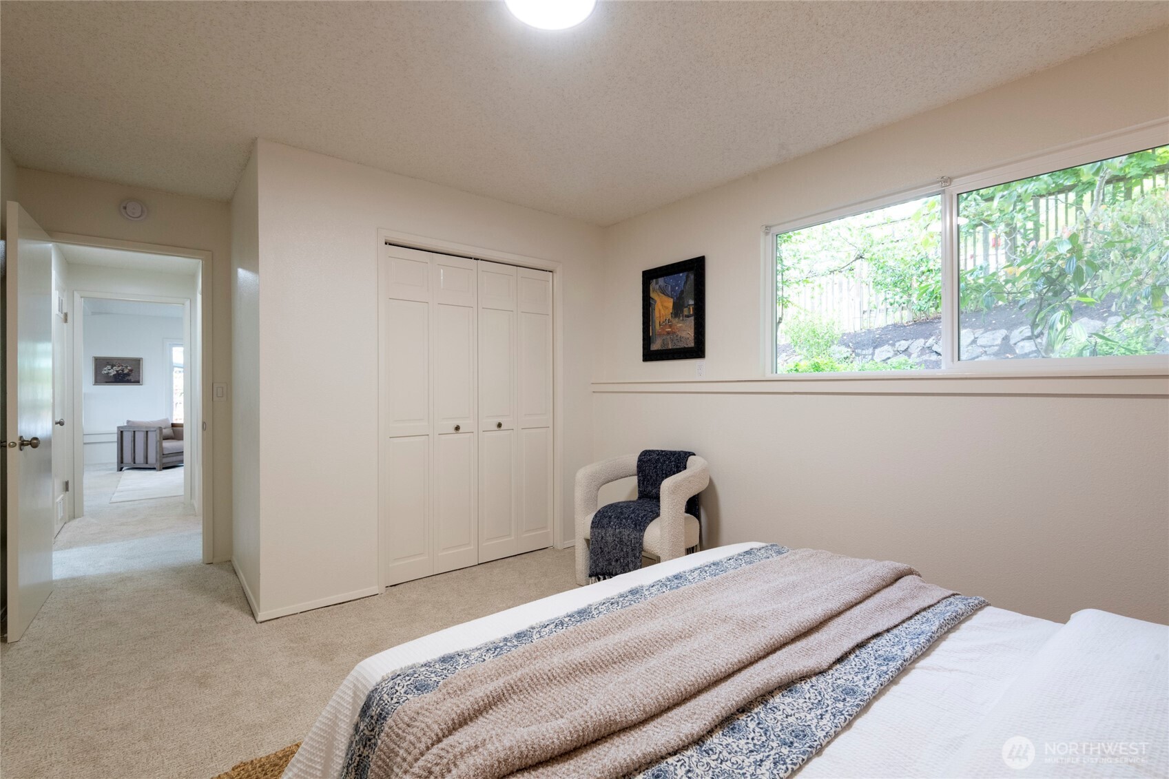 Bedroom with a large window, built-in closets, and a bed with a patterned blanket.
