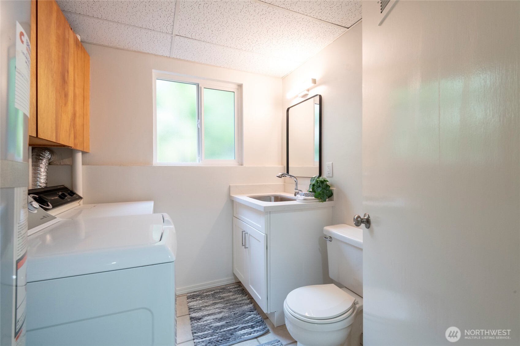 Laundry room with washer and dryer, wood cabinets, utility sink, and toilet.