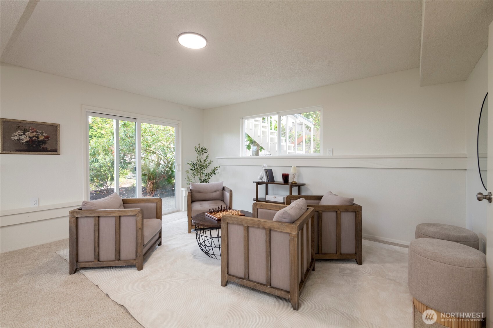 Furnished living room with wood-framed armchairs, a round coffee table, and sliding glass doors.
