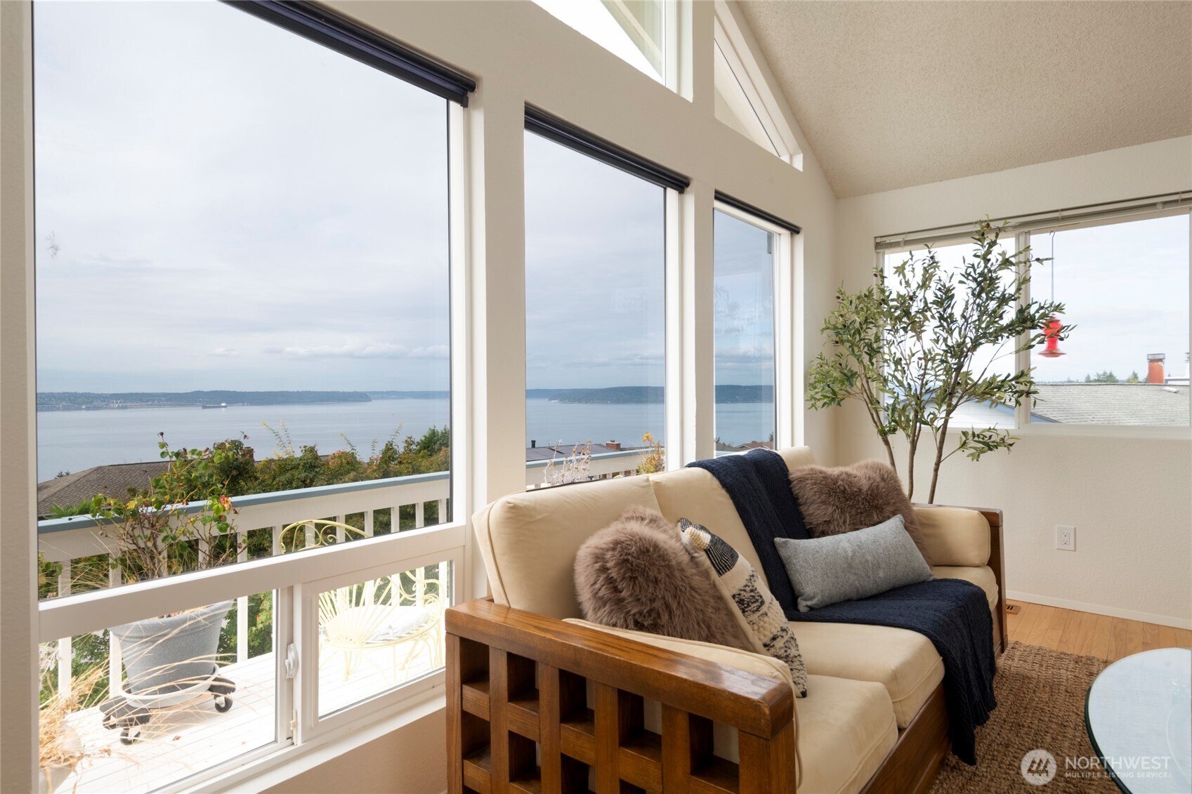 Living room with tall windows overlooking the water and a cream sofa.