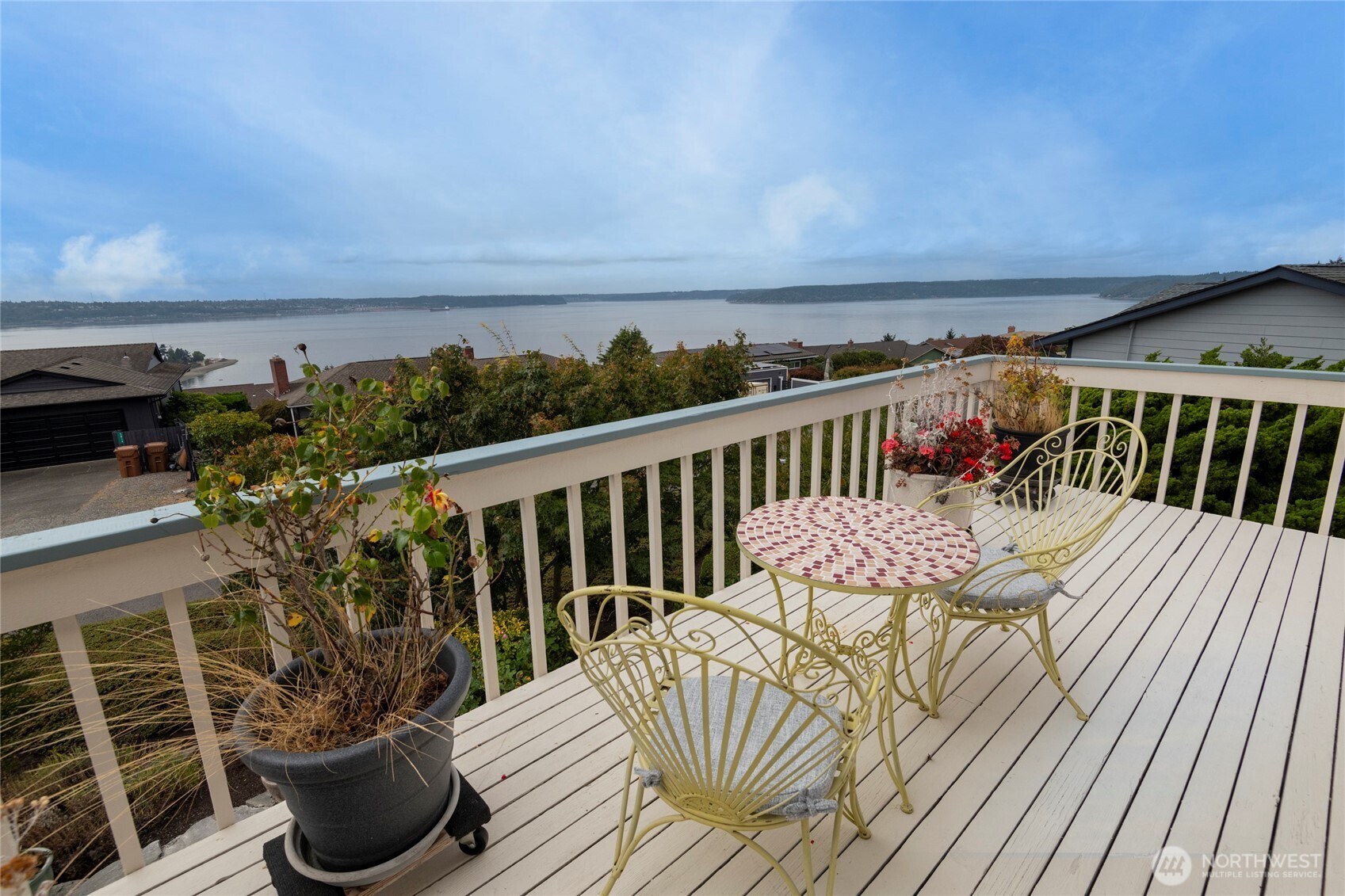 Deck with mosaic-top patio table and chairs overlooking the water.