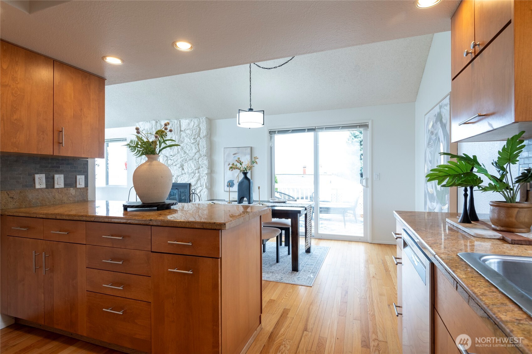 Kitchen with a granite island, warm wood cabinets, hardwood floors, and an adjoining dining area.