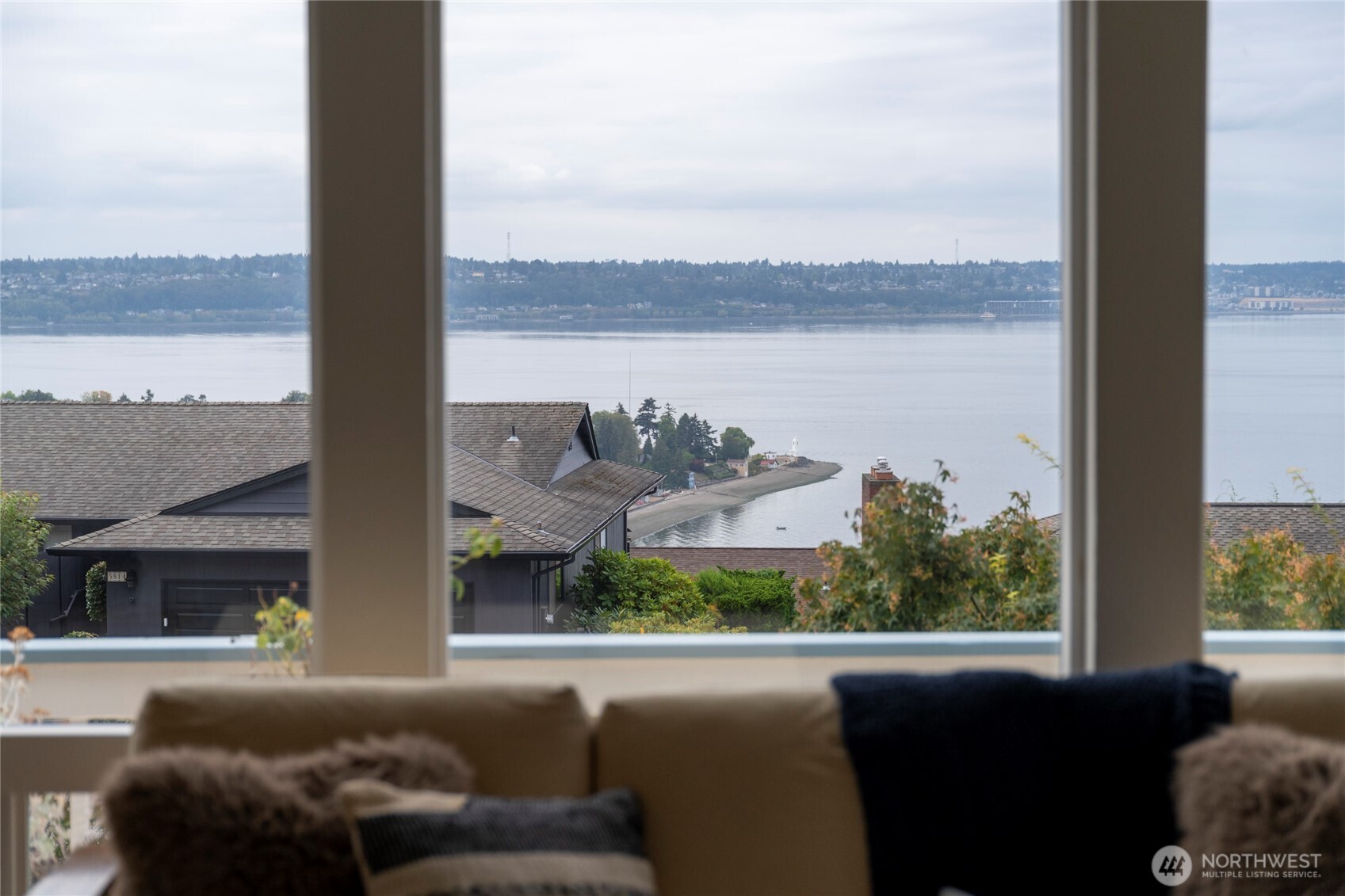 Living room window overlooks water and a curved shoreline, with a sofa in the foreground.
