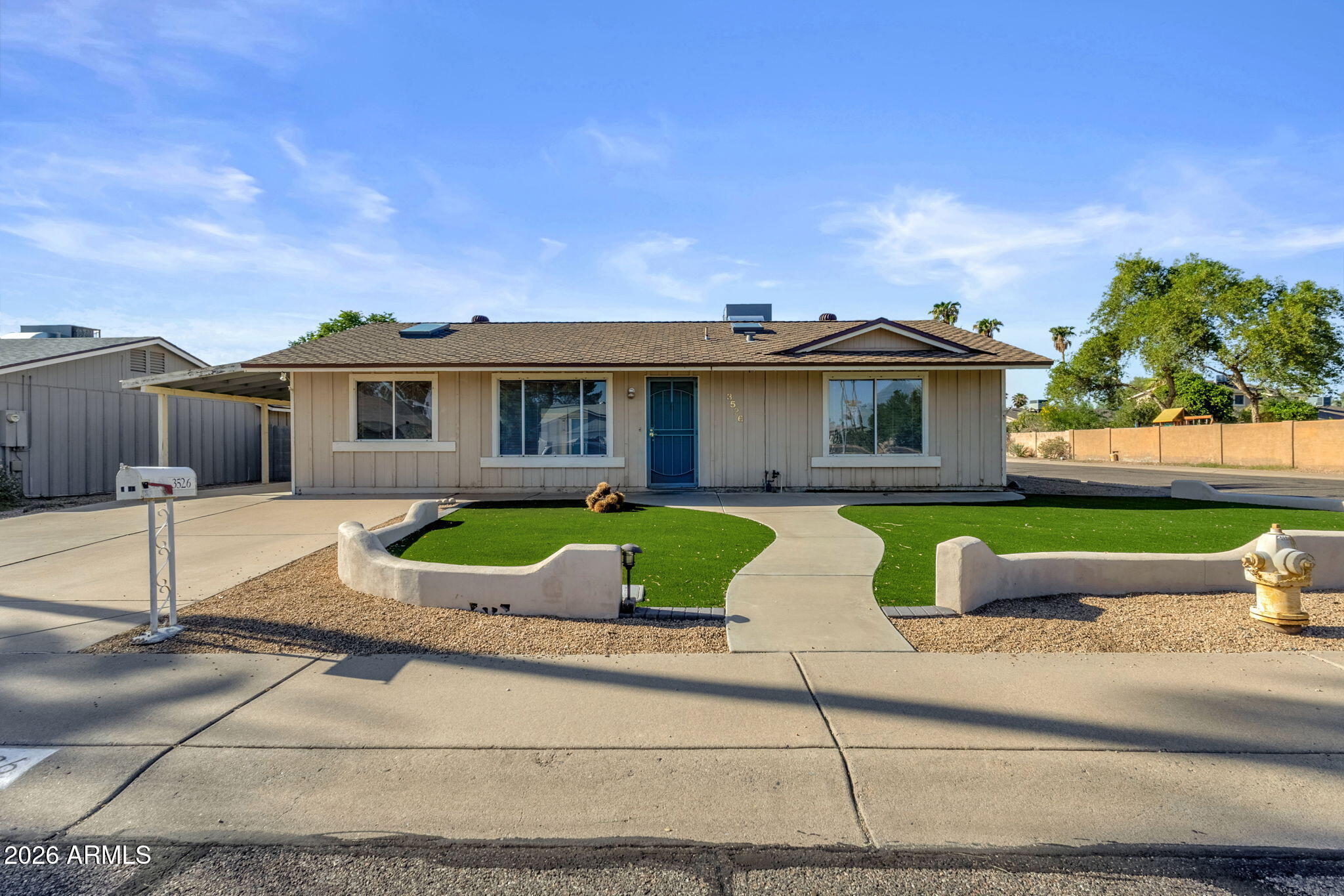 Single-story home with a blue front door, curved walkway, and landscaped front yard.