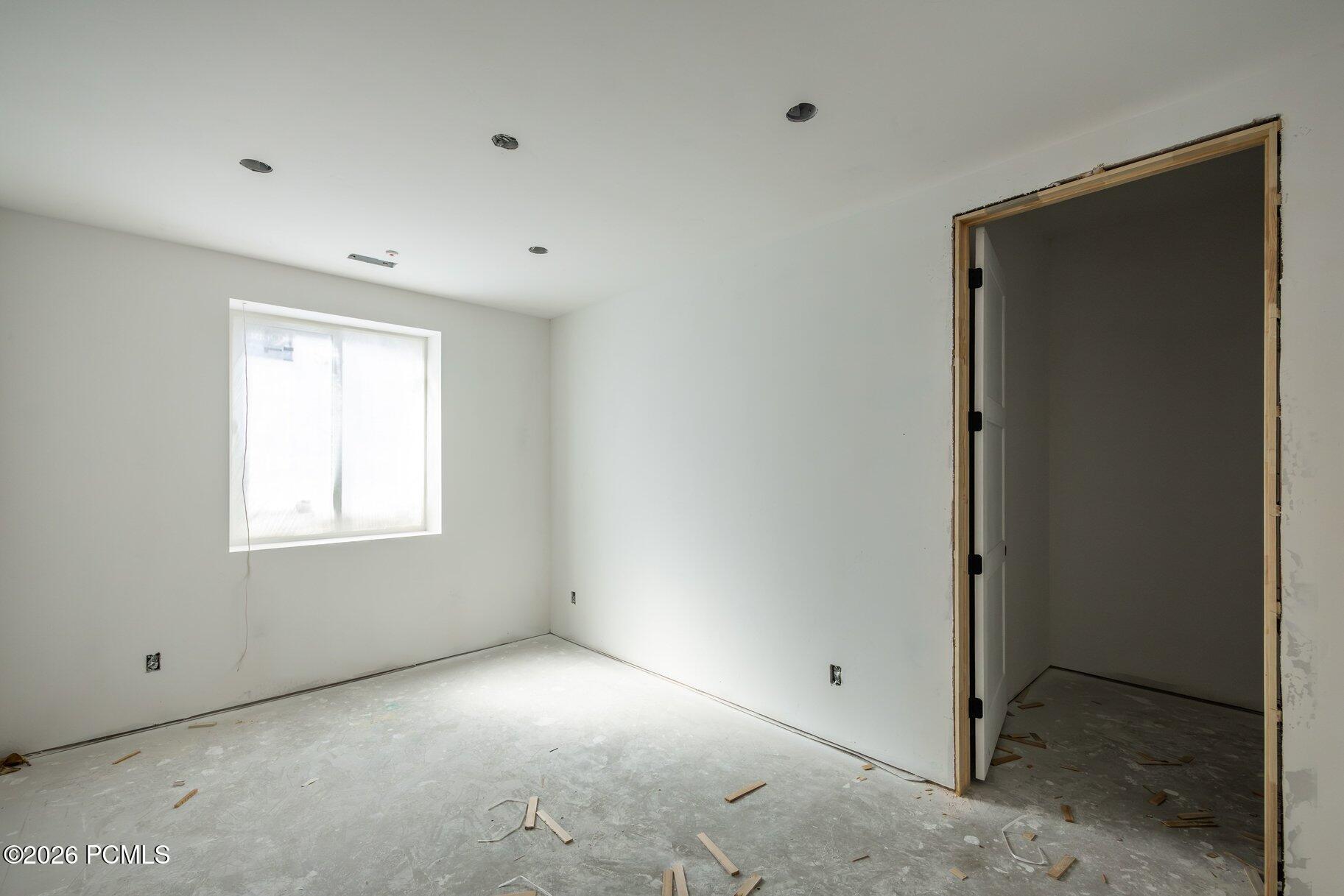 Unfinished room with a bare concrete floor, window, and untrimmed doorway.