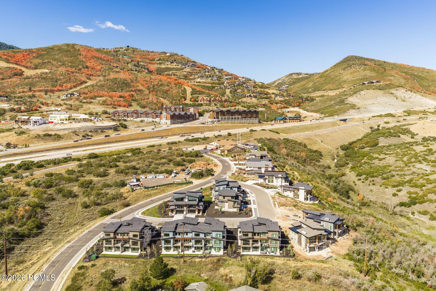 Aerial view of modern homes in a mountain neighborhood, with autumn hillsides and construction nearby.