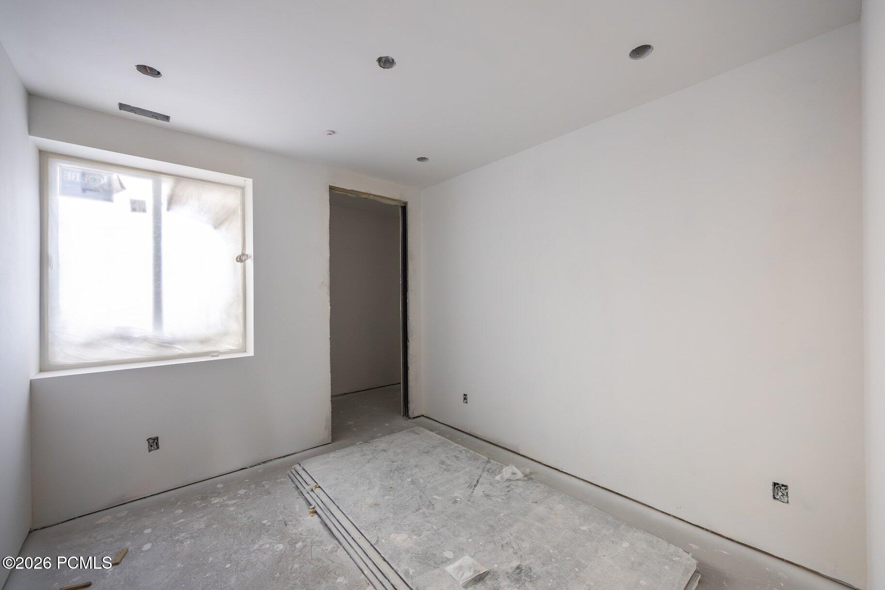 Unfinished room with a large window and construction materials on the floor.