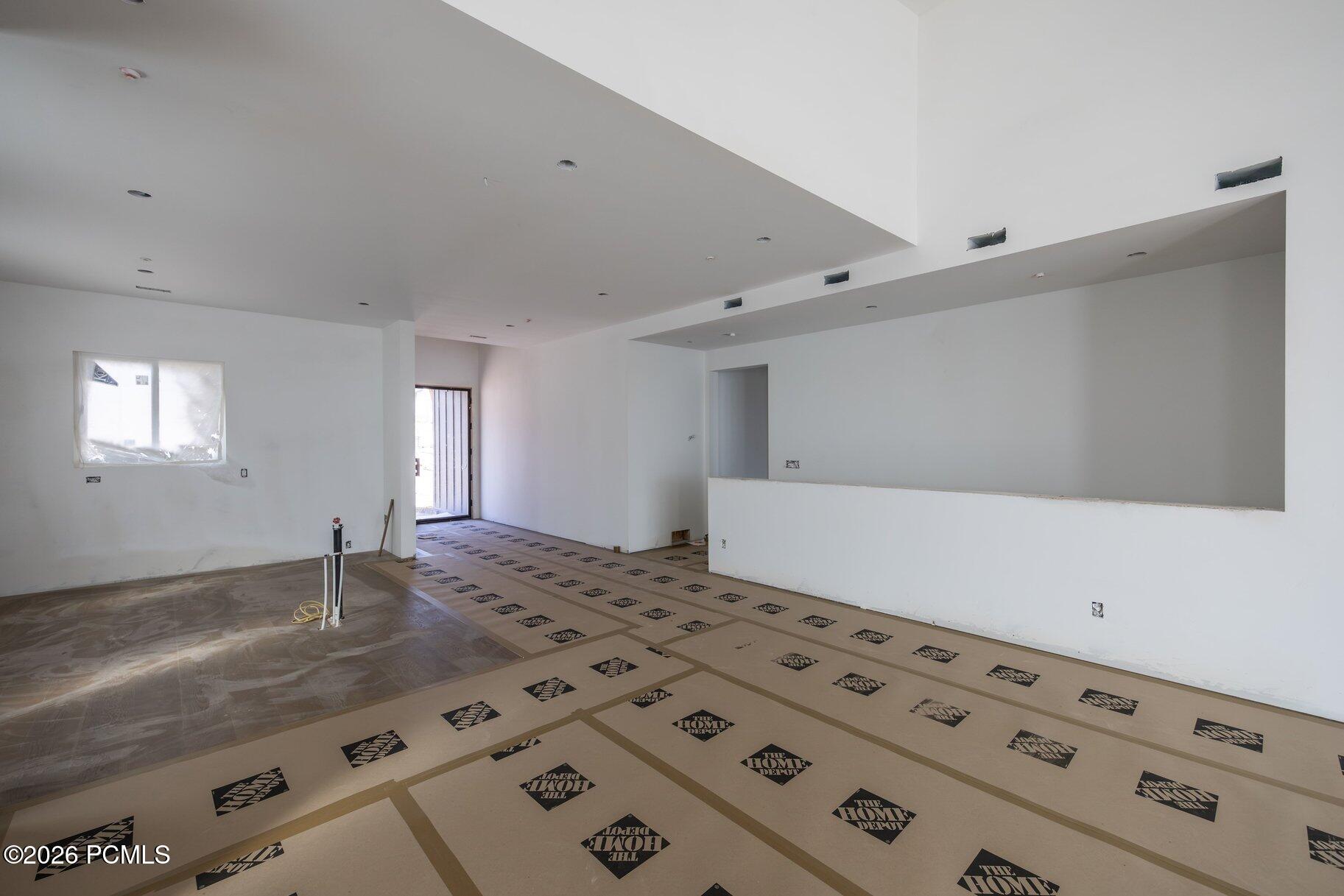 Unfinished open interior with protected flooring, recessed lights, and a wide pass-through opening.