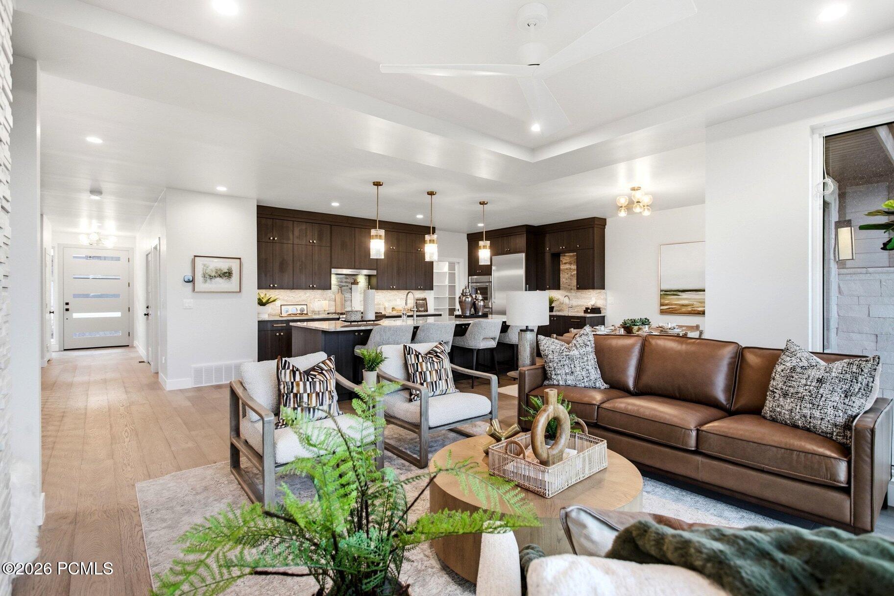 Open-plan living room and kitchen with dark wood cabinets, a large island, and a brown leather sofa.
