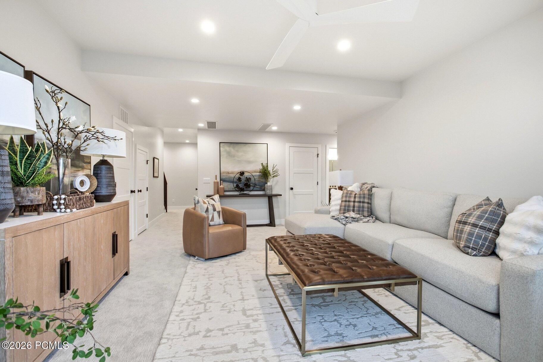 Staged living room with a light-gray sectional and tufted leather coffee table.