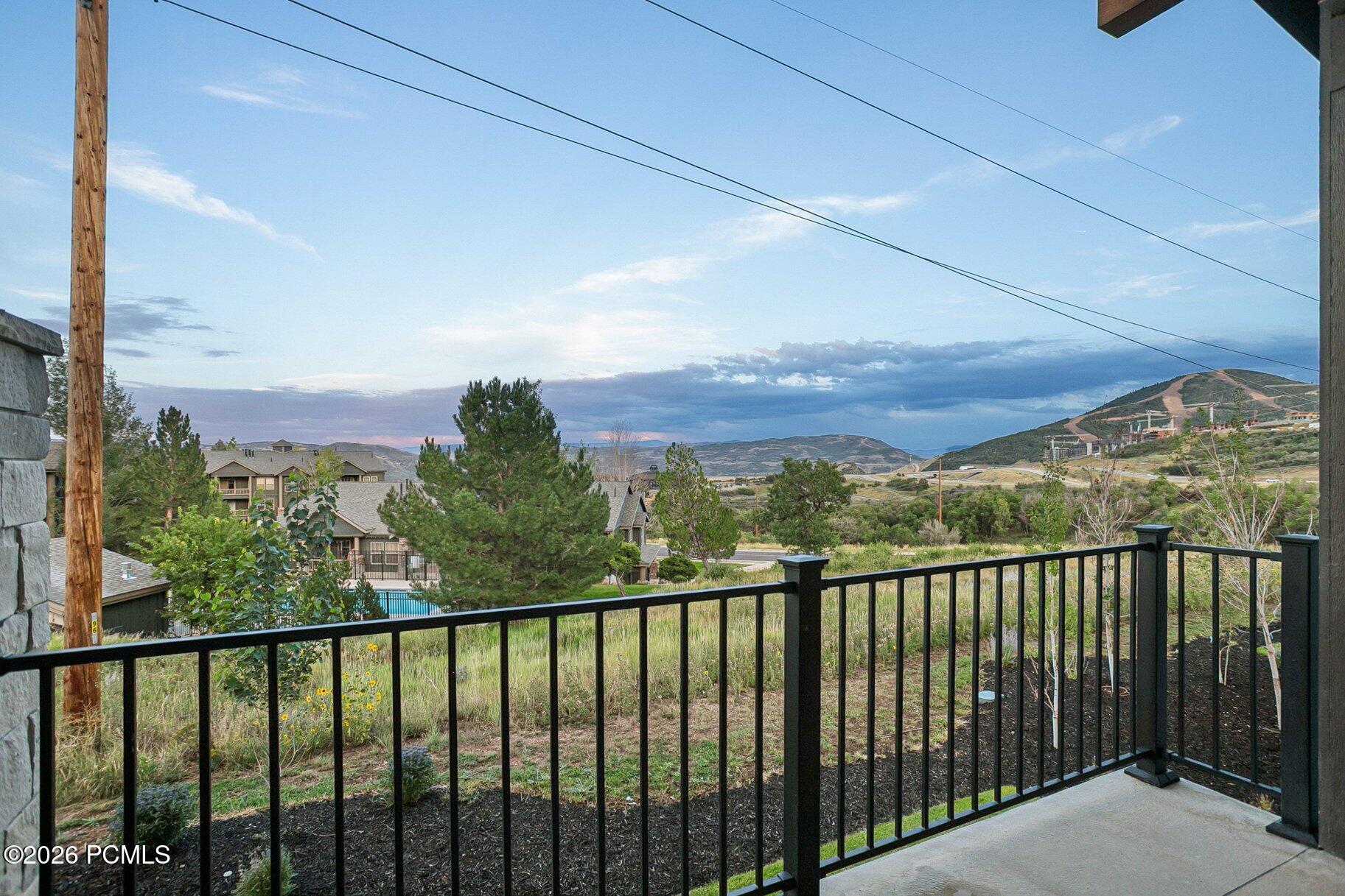 Balcony overlooking rolling hills, neighboring homes, and a distant construction area.