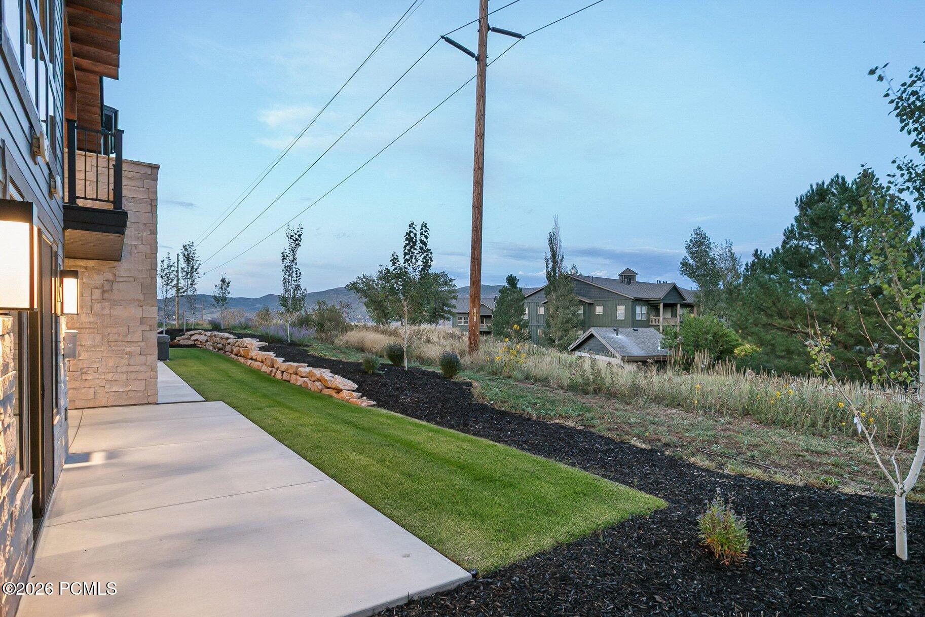 Home exterior with a wide concrete walkway, landscaped lawn, and distant mountain views.
