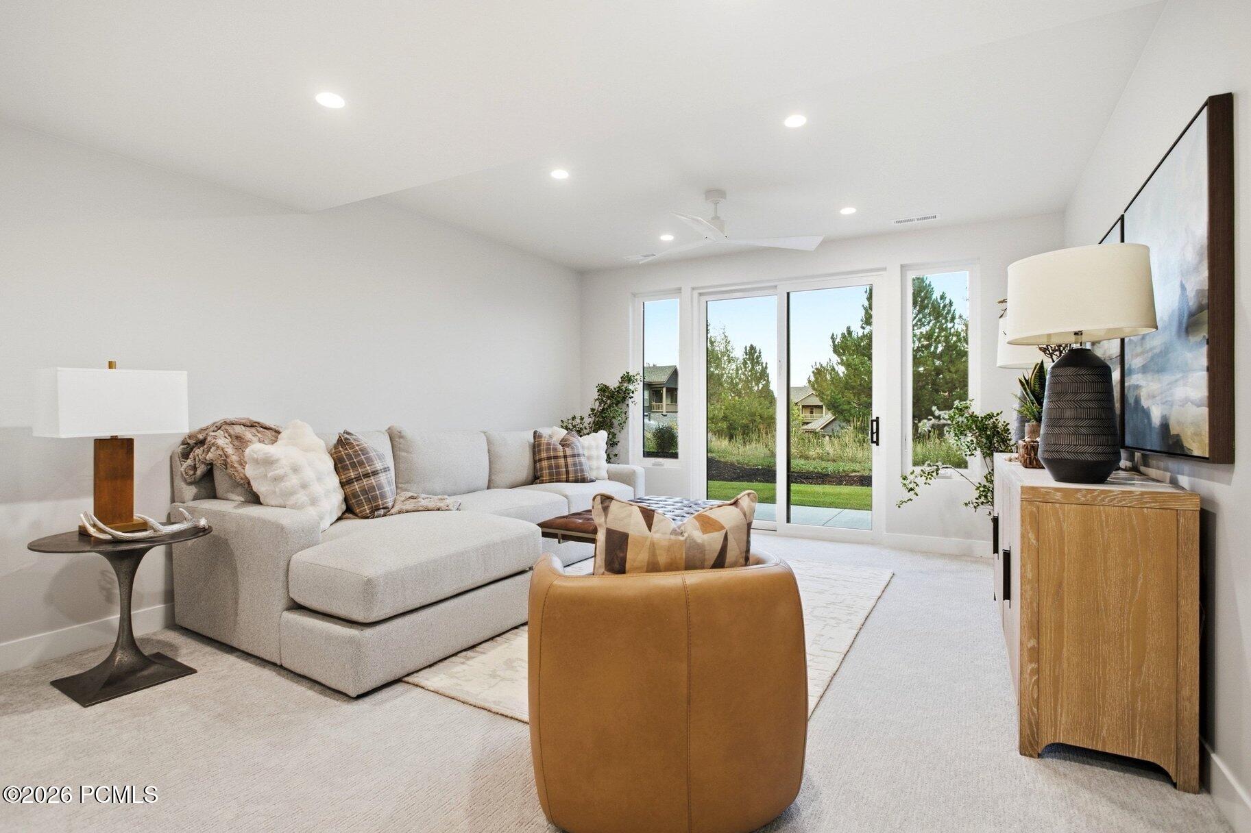 Living room with a light-gray sectional, tan leather chair, and sliding glass doors to a patio.