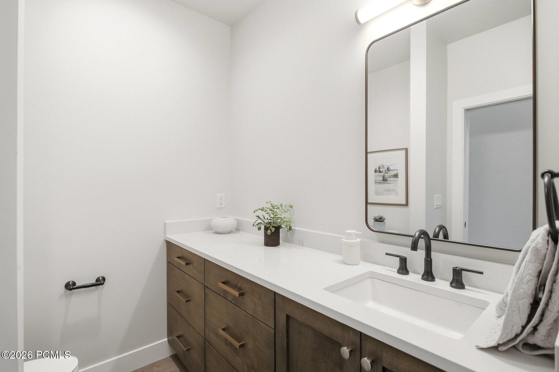 Bathroom with a dark wood vanity, white countertop, and large mirror.
