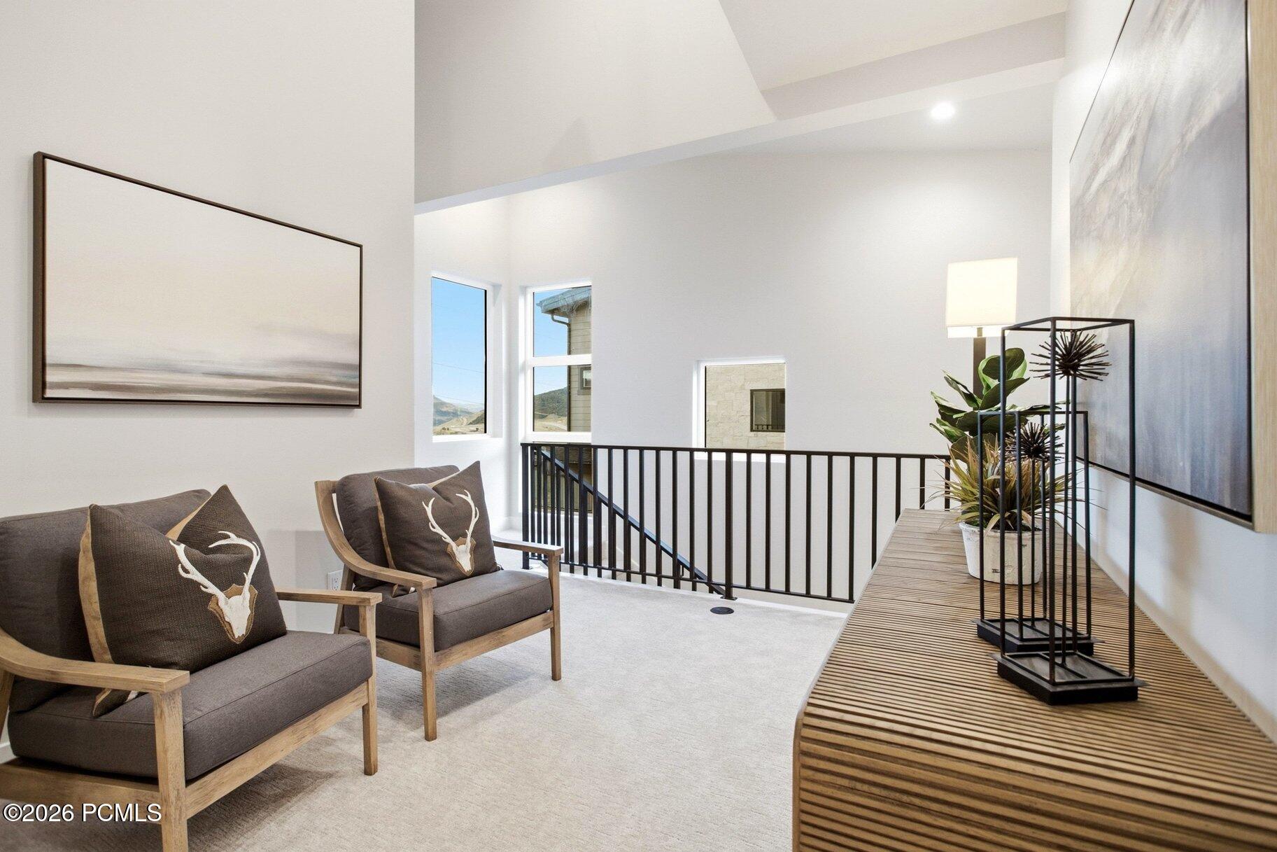 Upstairs sitting area with gray armchairs, a slatted console table, and mountain views through tall windows.