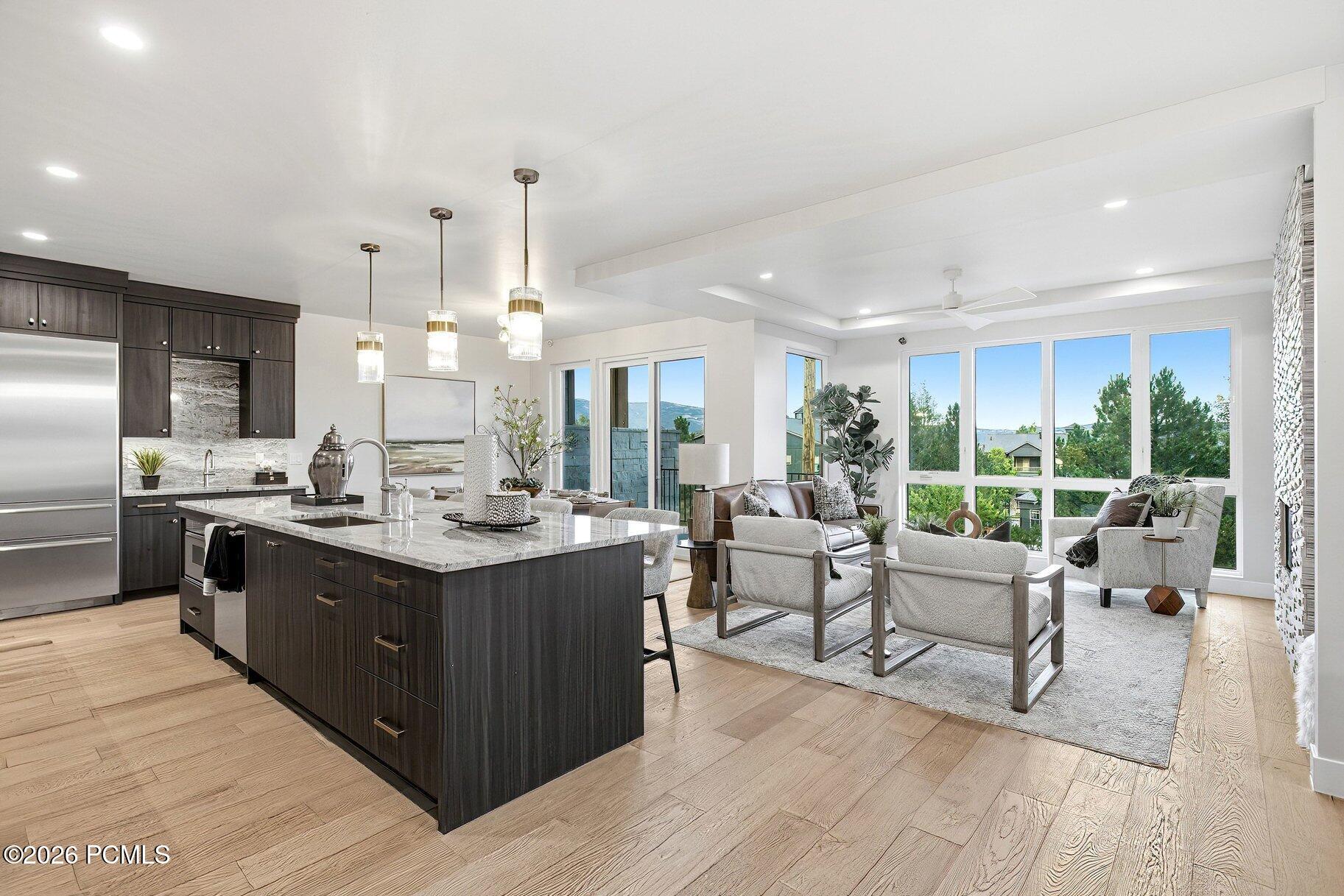 Open-plan kitchen and living room with a large marble island and expansive windows.