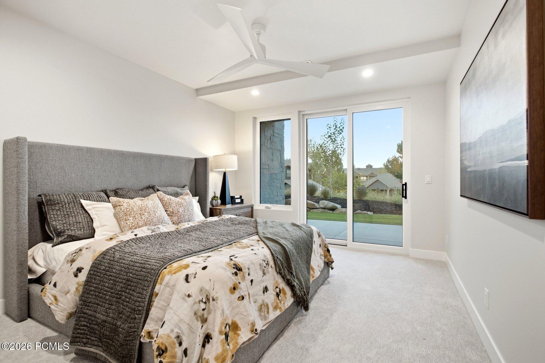 Staged bedroom with a gray upholstered bed and sliding glass door to a patio.