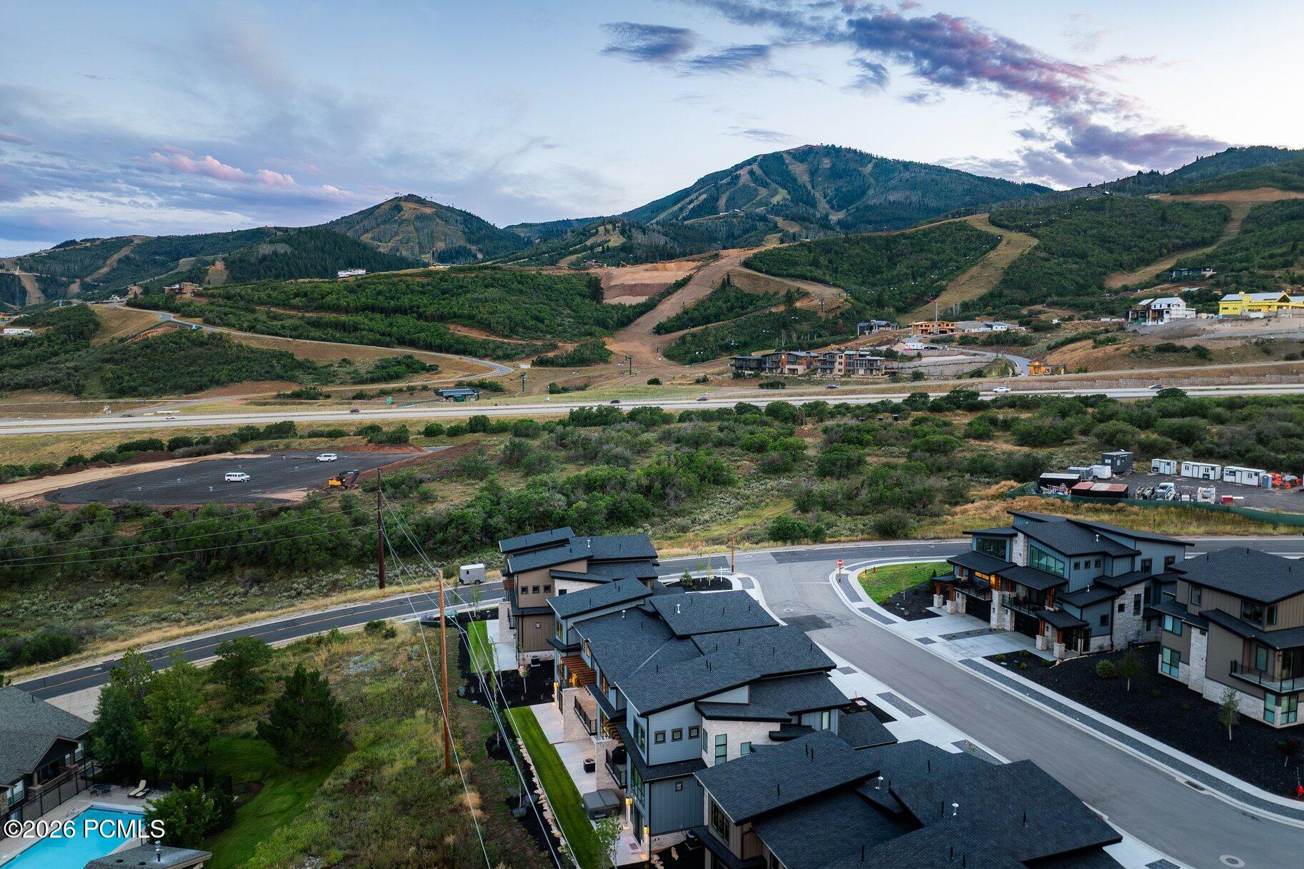 Aerial view of modern homes with wooded mountain slopes beyond the neighborhood.