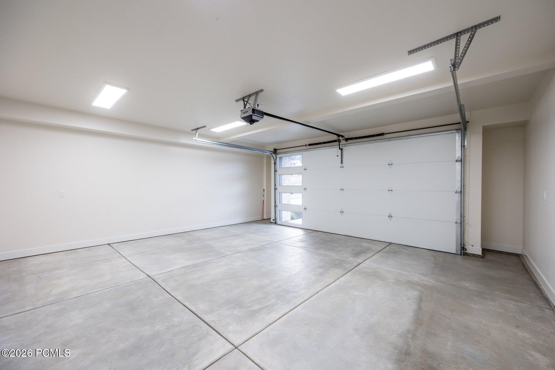Empty garage with a concrete floor and closed white garage door.