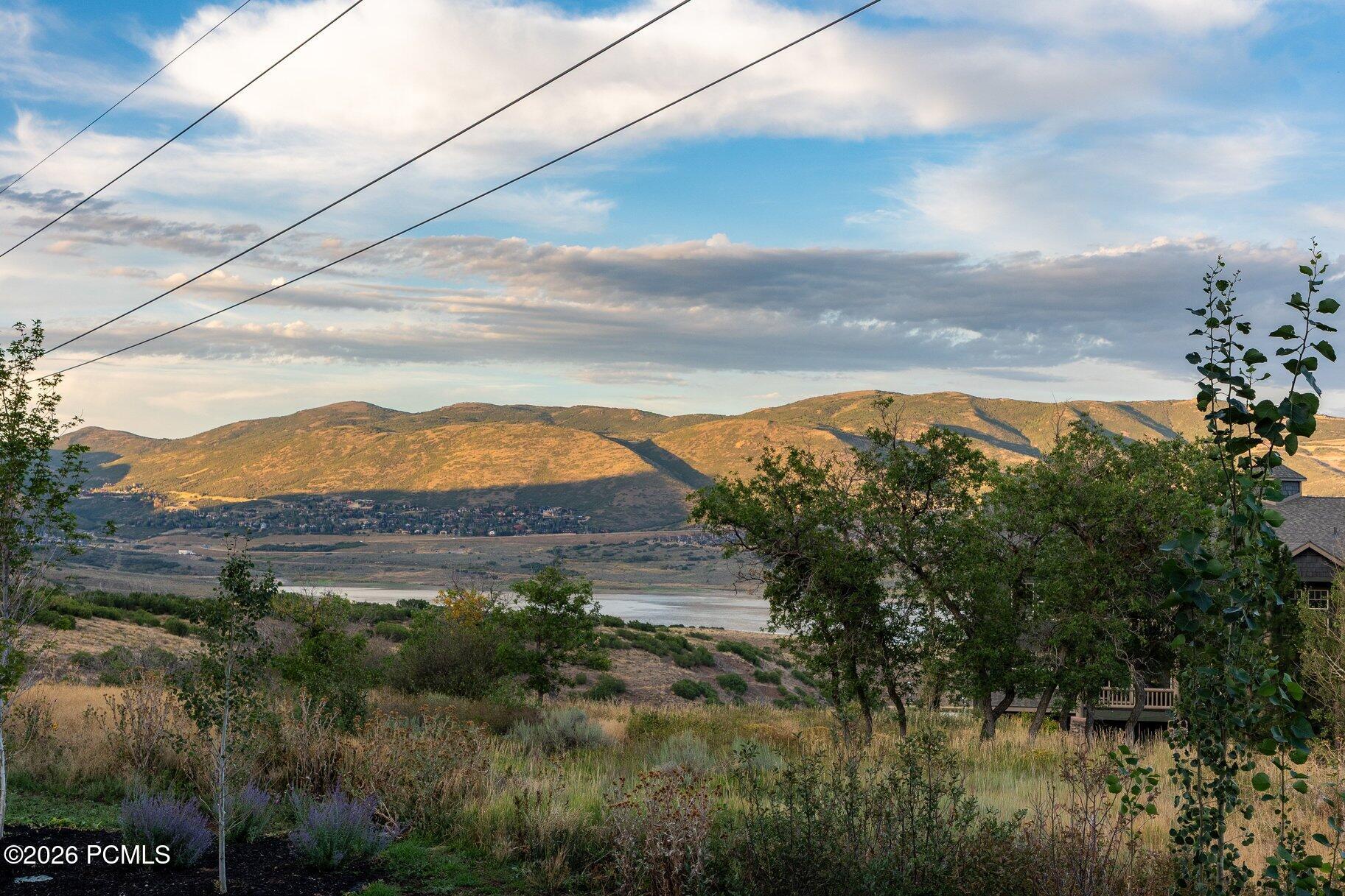 Panoramic mountain and reservoir view from the property, framed by hillside landscaping and crossed by utility lines.