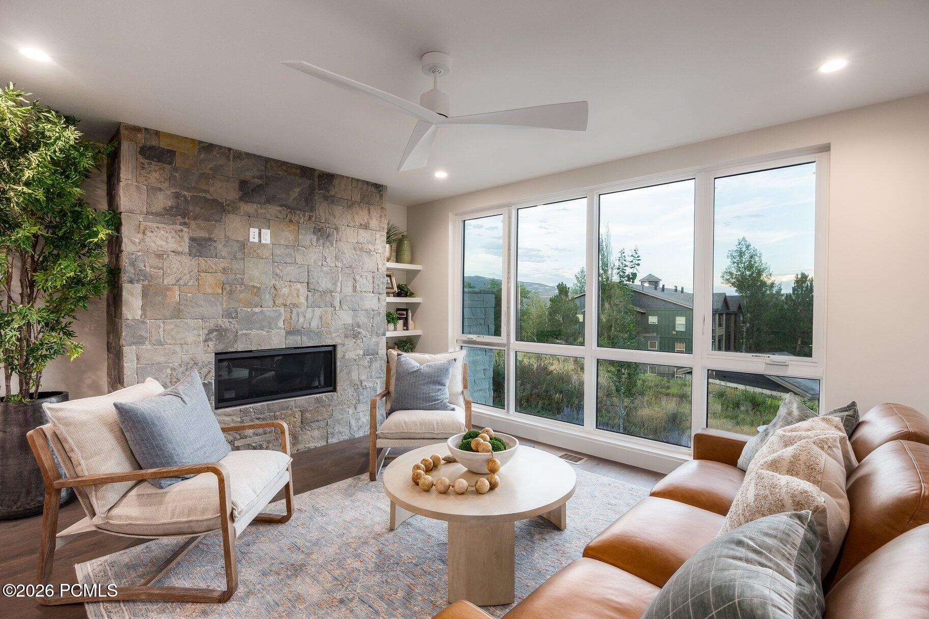 Living room with a stone fireplace, expansive windows, and a leather sofa.
