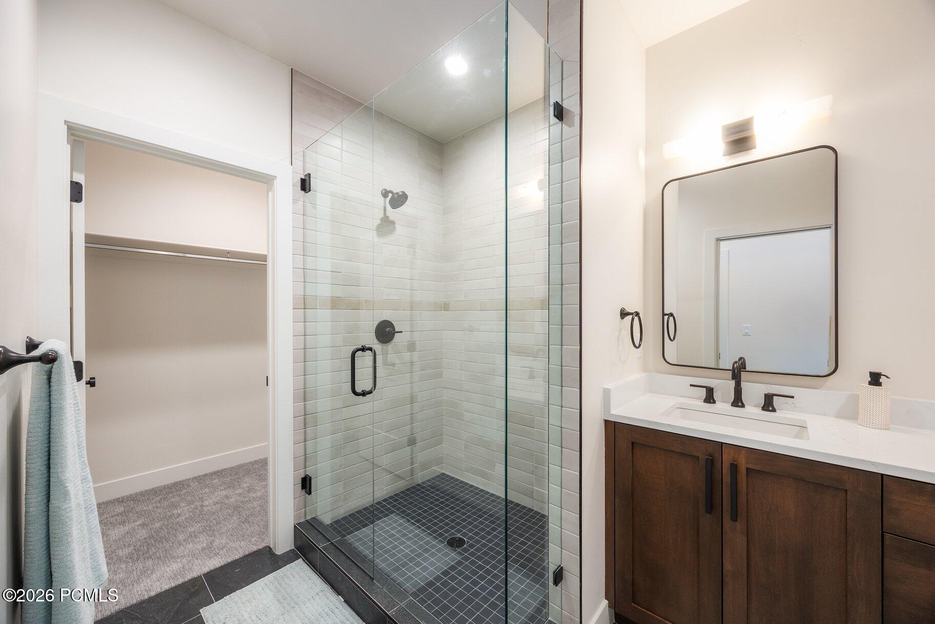 Bathroom with glass walk-in shower, tiled walls, and dark wood vanity.