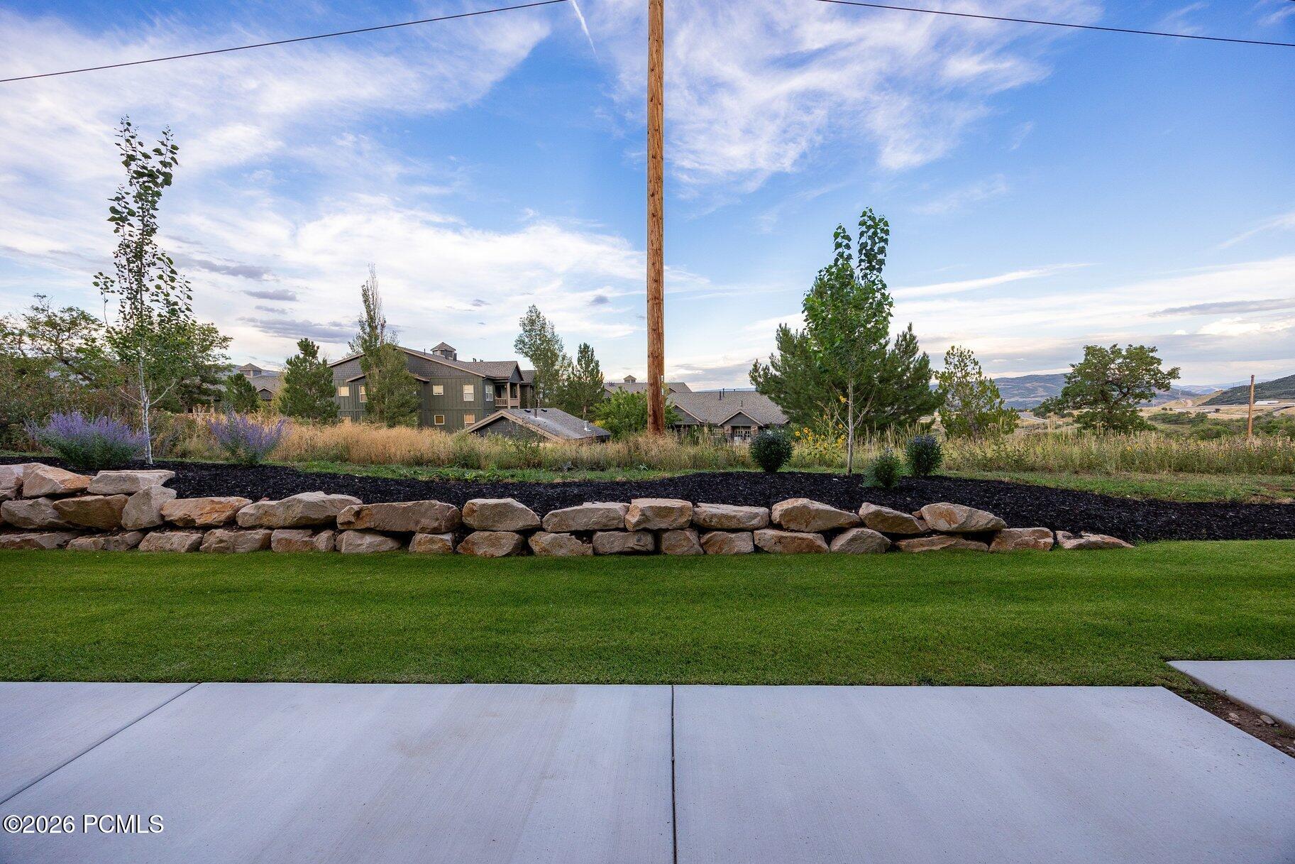 Landscaped lawn and stone wall with neighboring homes and distant mountain views.