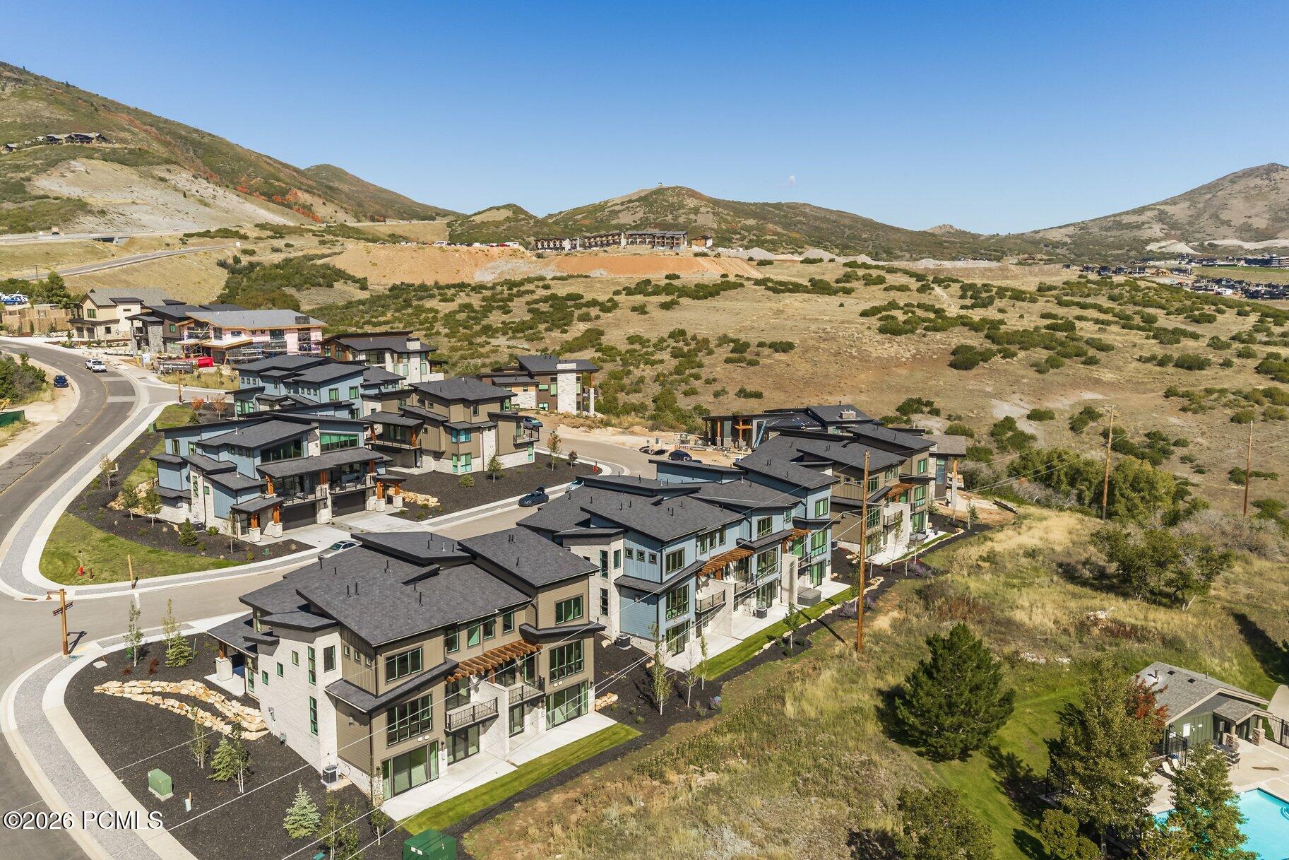 Aerial view of modern homes in a mountain neighborhood, with curving streets and hills beyond.