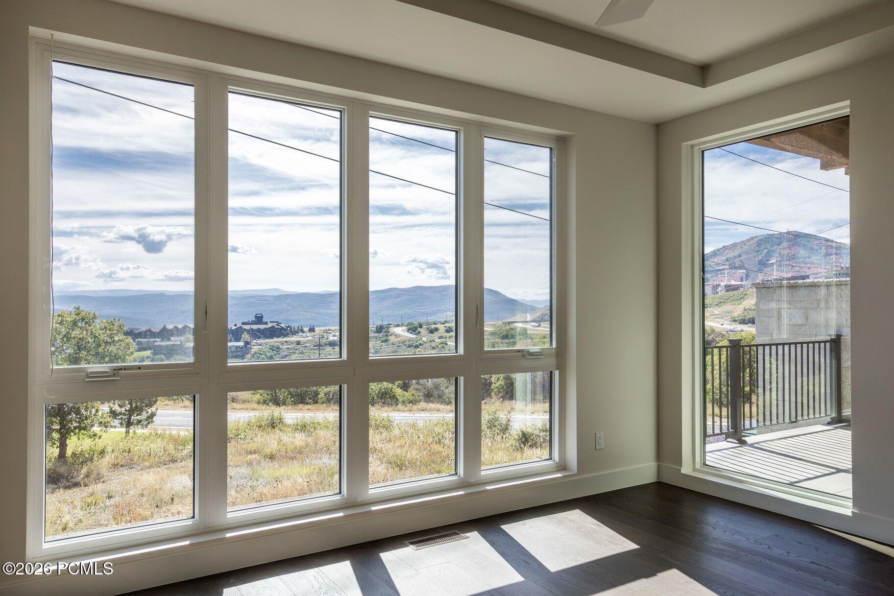 Empty room with expansive windows, a balcony, and mountain views.