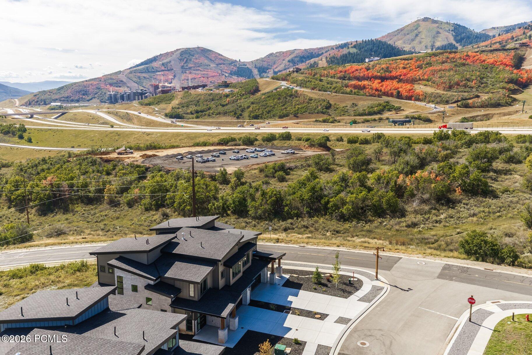 Aerial view of a contemporary home below autumn-colored hills and mountain slopes.