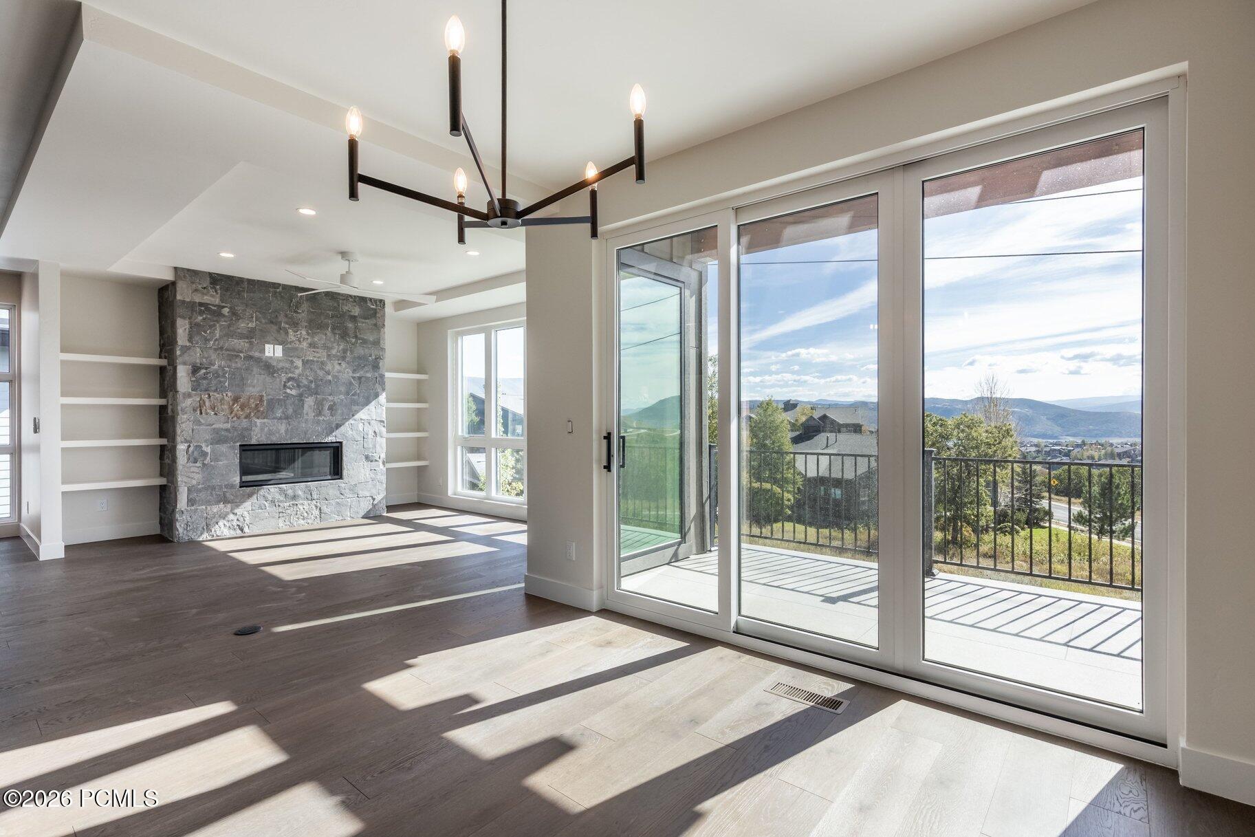 Living room with a stone fireplace and sliding doors to a balcony overlooking mountains.