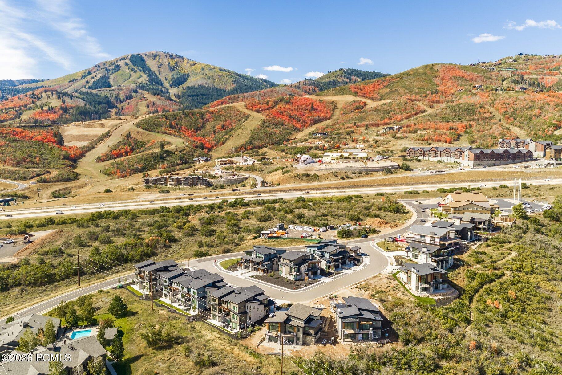Aerial view of modern homes below colorful autumn hills and mountains.