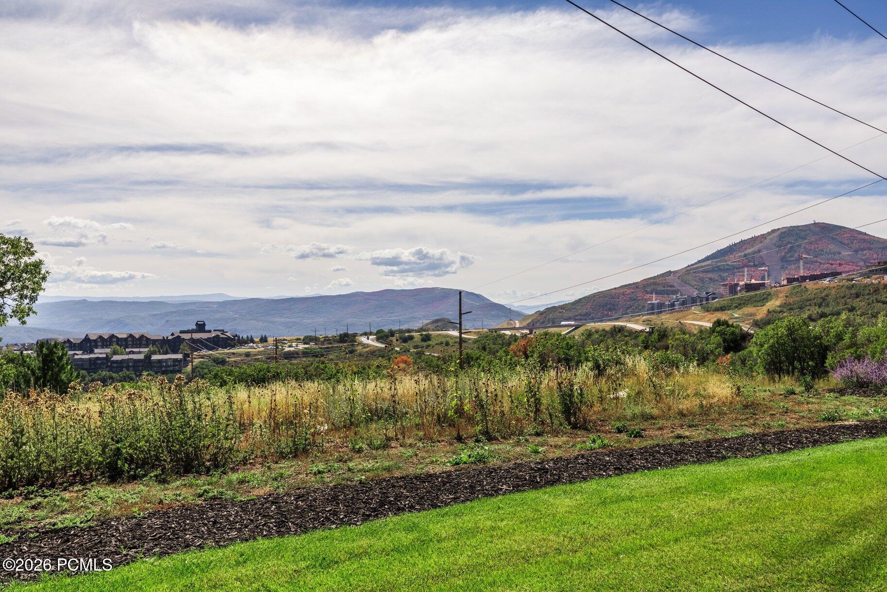 Panoramic mountain view over a landscaped hillside, with nearby buildings and autumn-colored slopes.